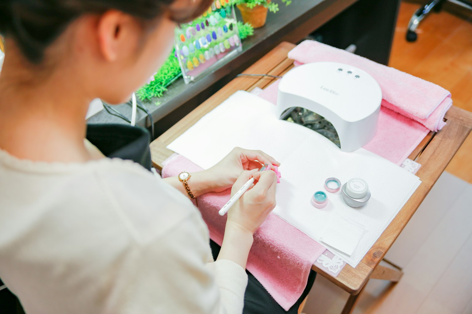 Donna che applica nail art con forniture e lampada UV su un tavolo da lavoro