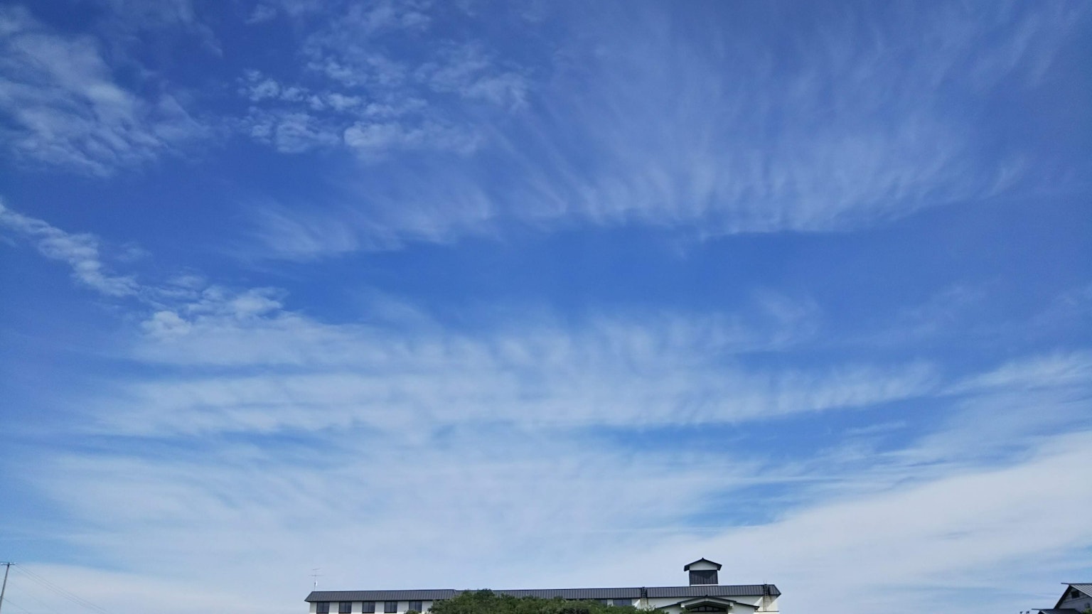 Ein Gebäude hebt sich vor einem blauen Himmel und weißen Wolken ab