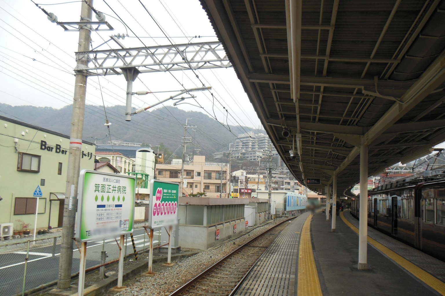 ชานชาลาสถานีรถไฟที่เงียบสงบพร้อมอาคารและภูเขารอบๆ