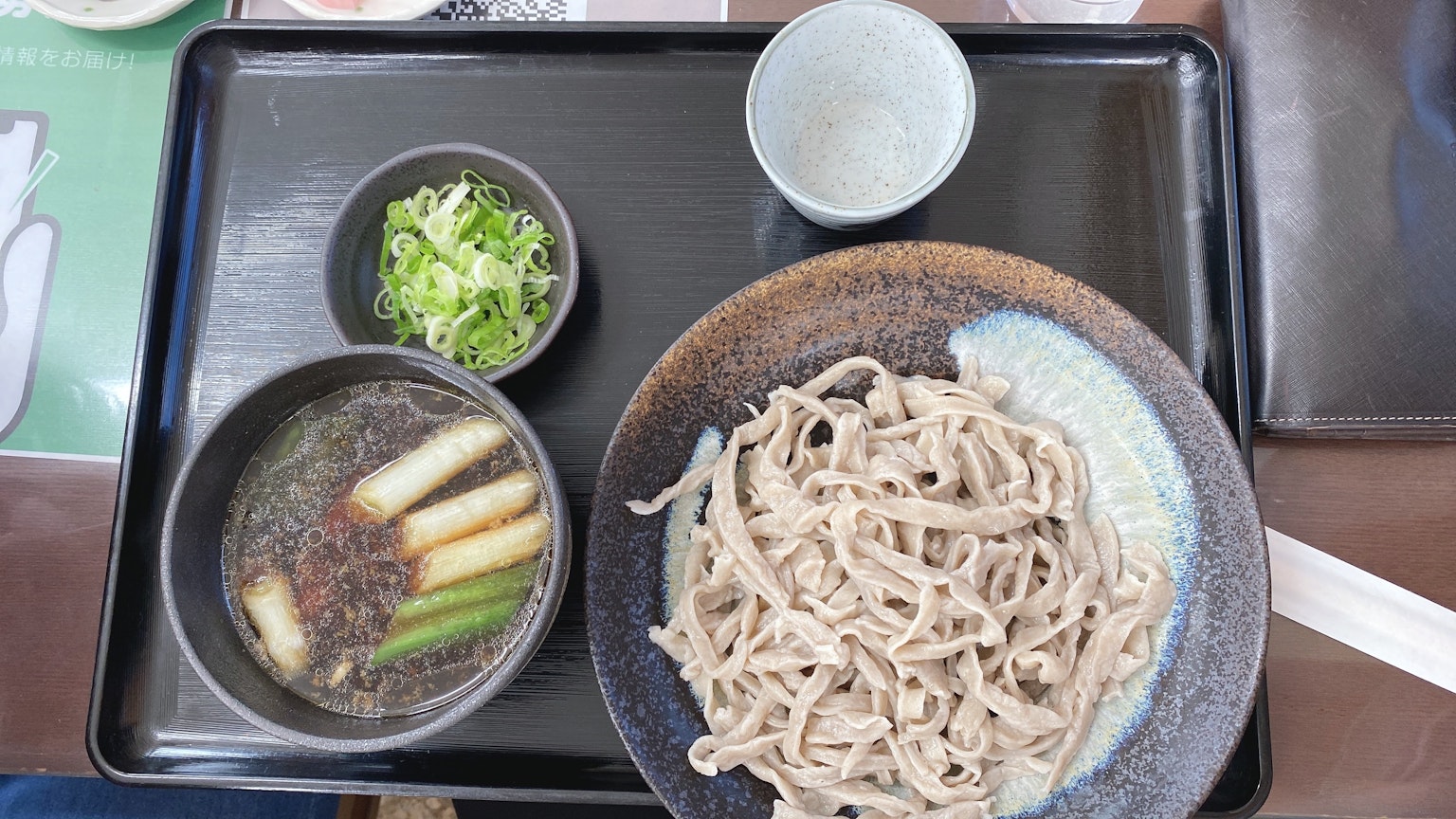 Một đĩa mì soba với nước chấm và hành lá trên khay