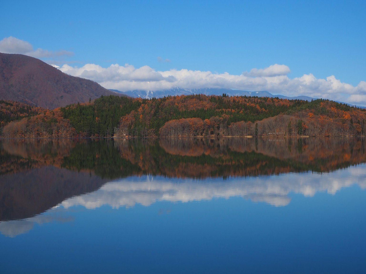 Scenic view of a lake reflecting autumn foliage and blue sky