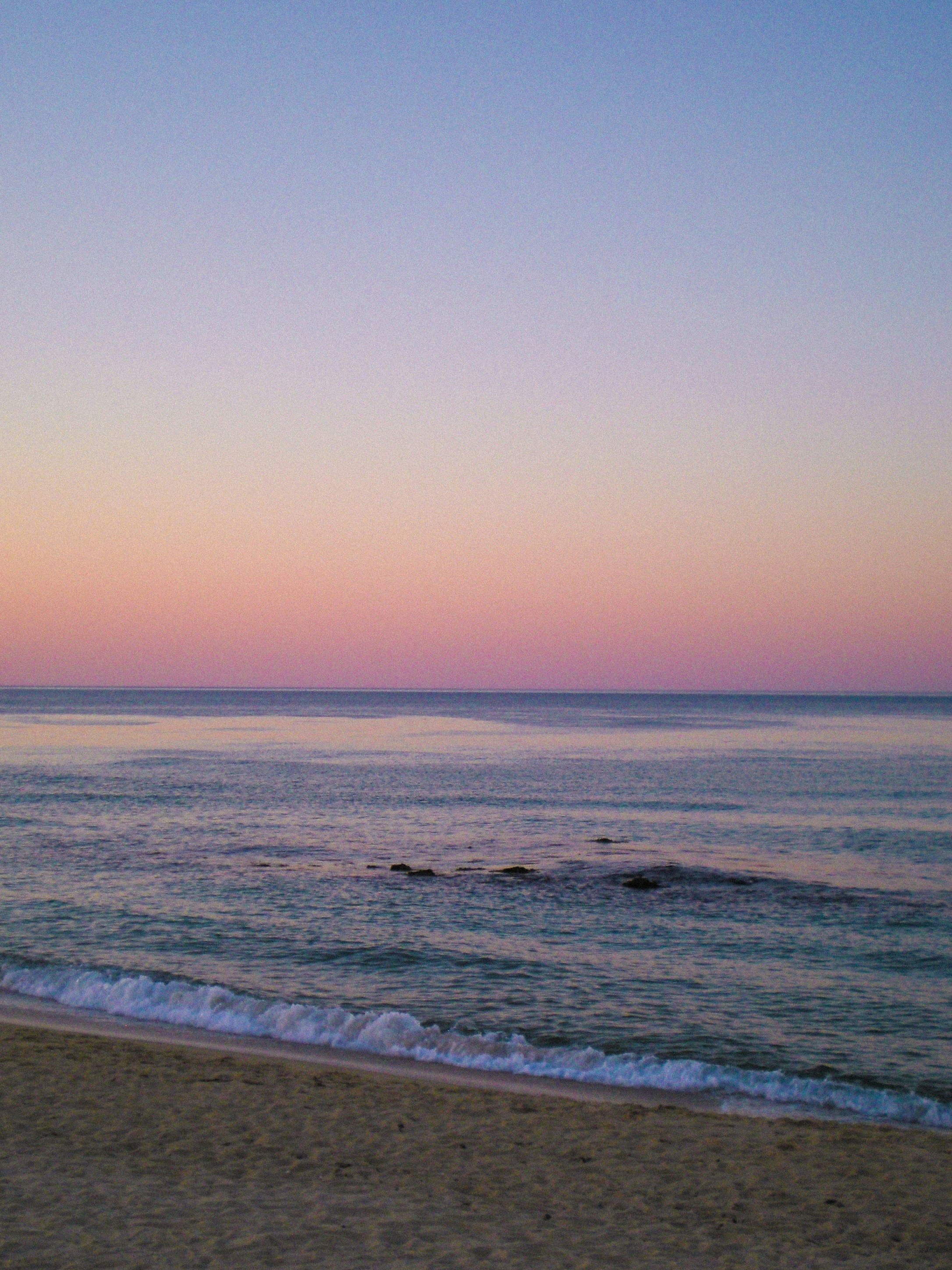 夕暮れの海辺に波が打ち寄せる風景