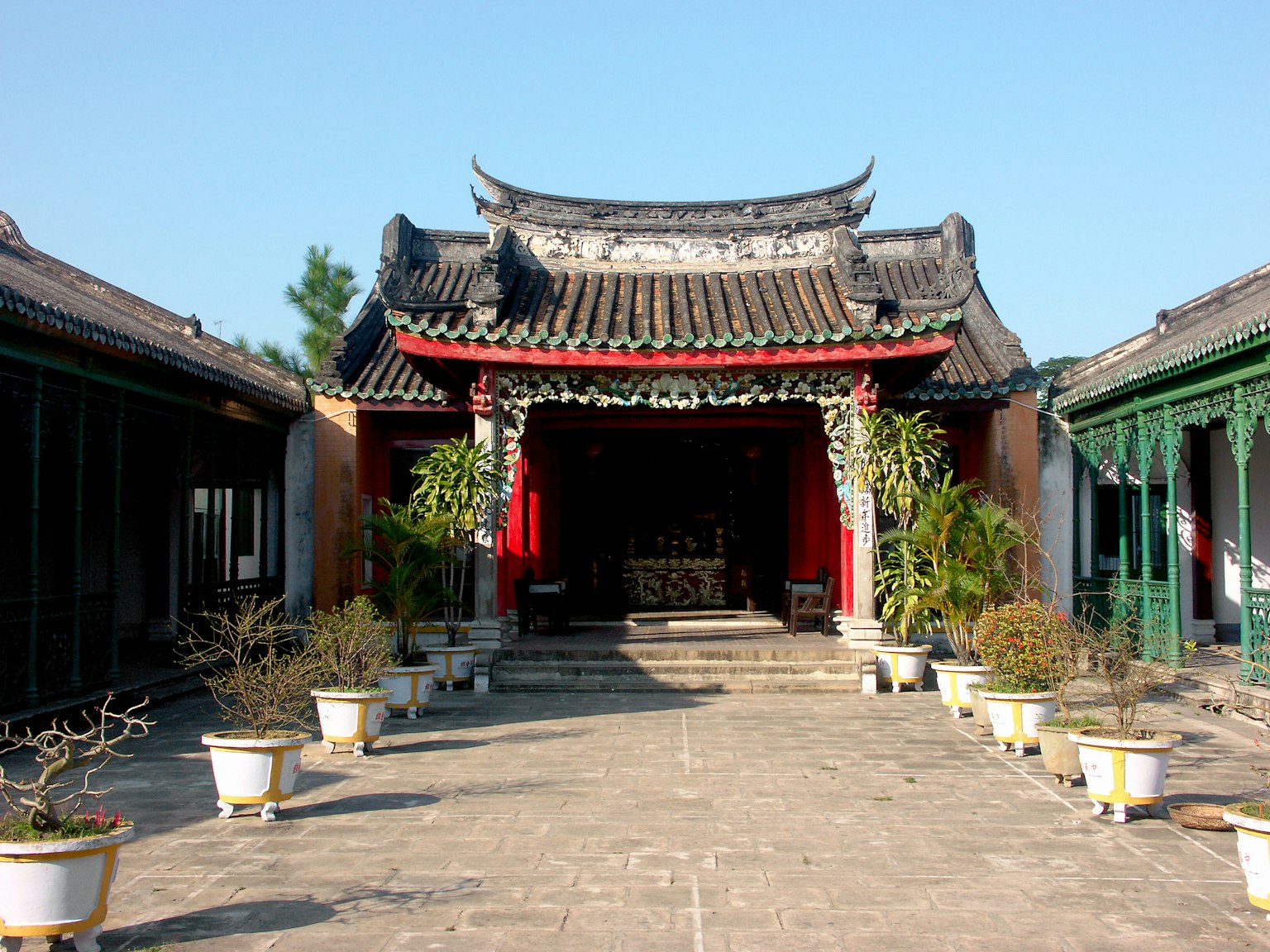 Vista dell'ingresso di un tempio cinese tradizionale con tetto decorativo e giardino circostante