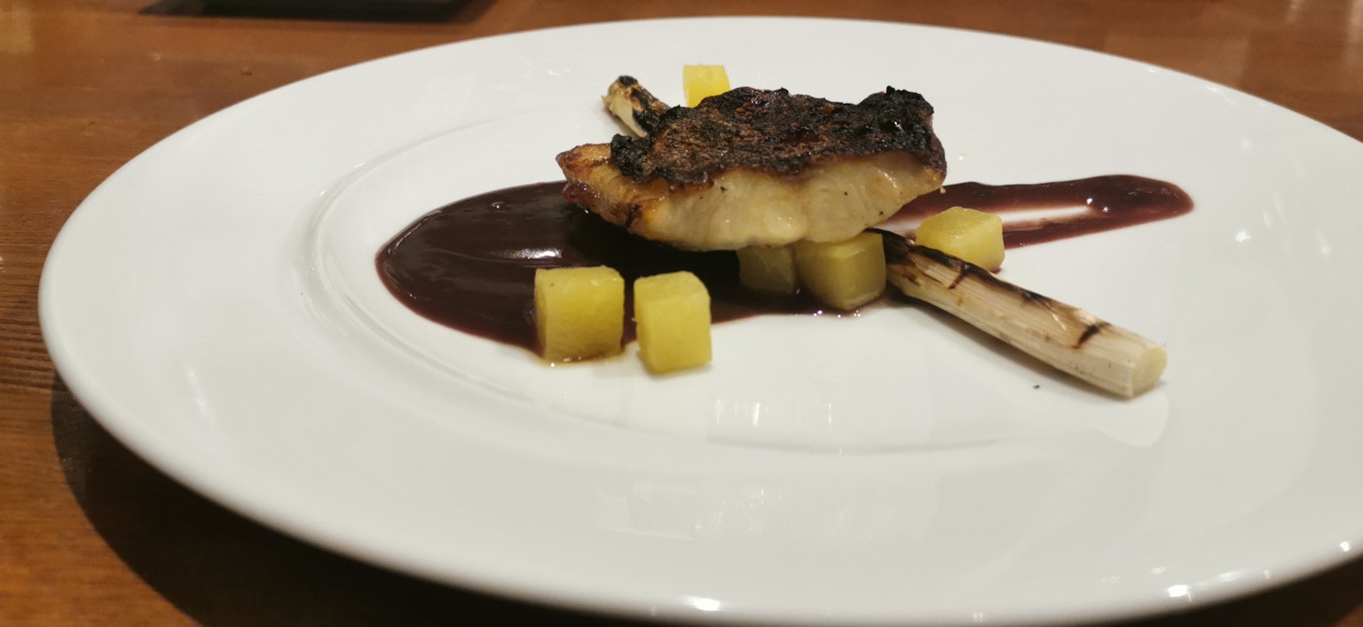 A beautifully plated dish featuring a seared fish fillet with sauce accompanied by diced vegetables