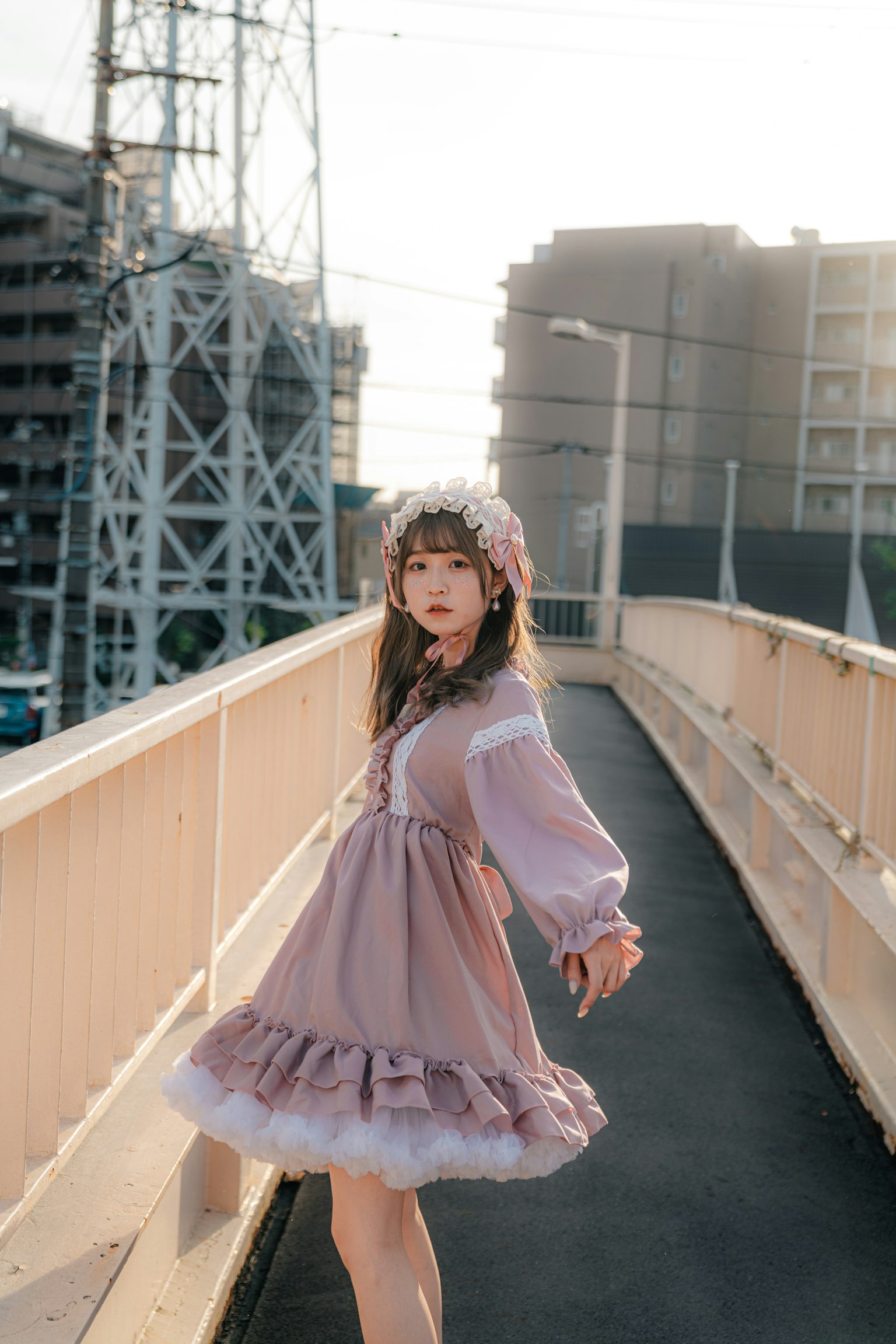 Una chica con un vestido rosa lindo posando en un puente