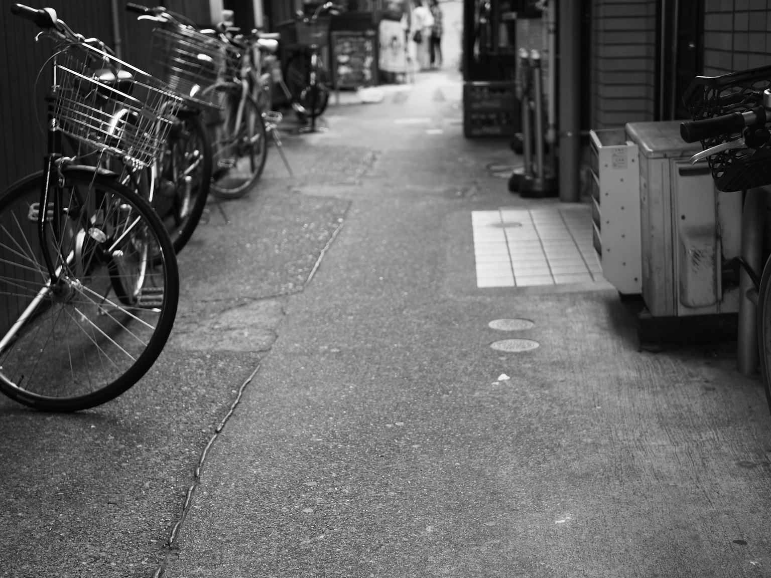 Narrow alley with parked bicycles and a quiet atmosphere in black and white