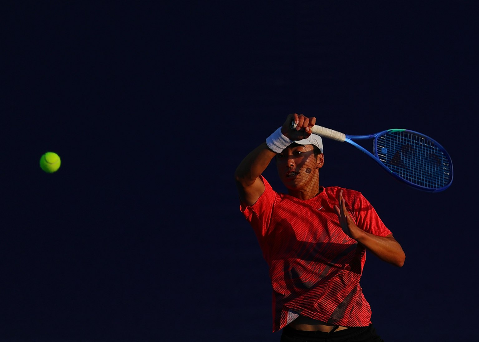 Tennis Spieler bereitet sich darauf vor, einen leuchtend grünen Ball mit einem blauen Schläger zu schlagen