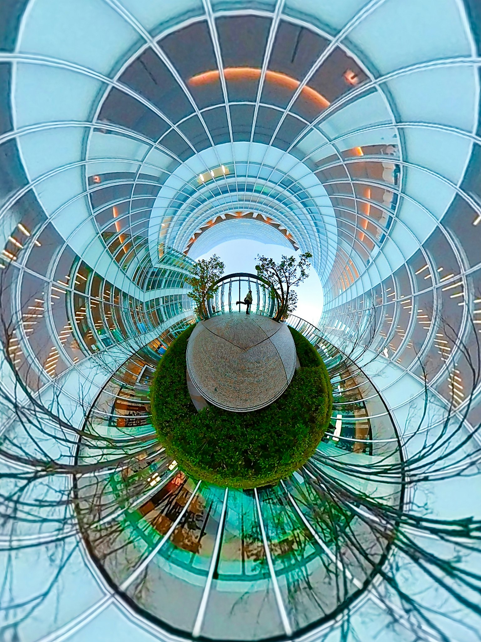 Modern circular glass structure with vibrant greenery and unique perspective