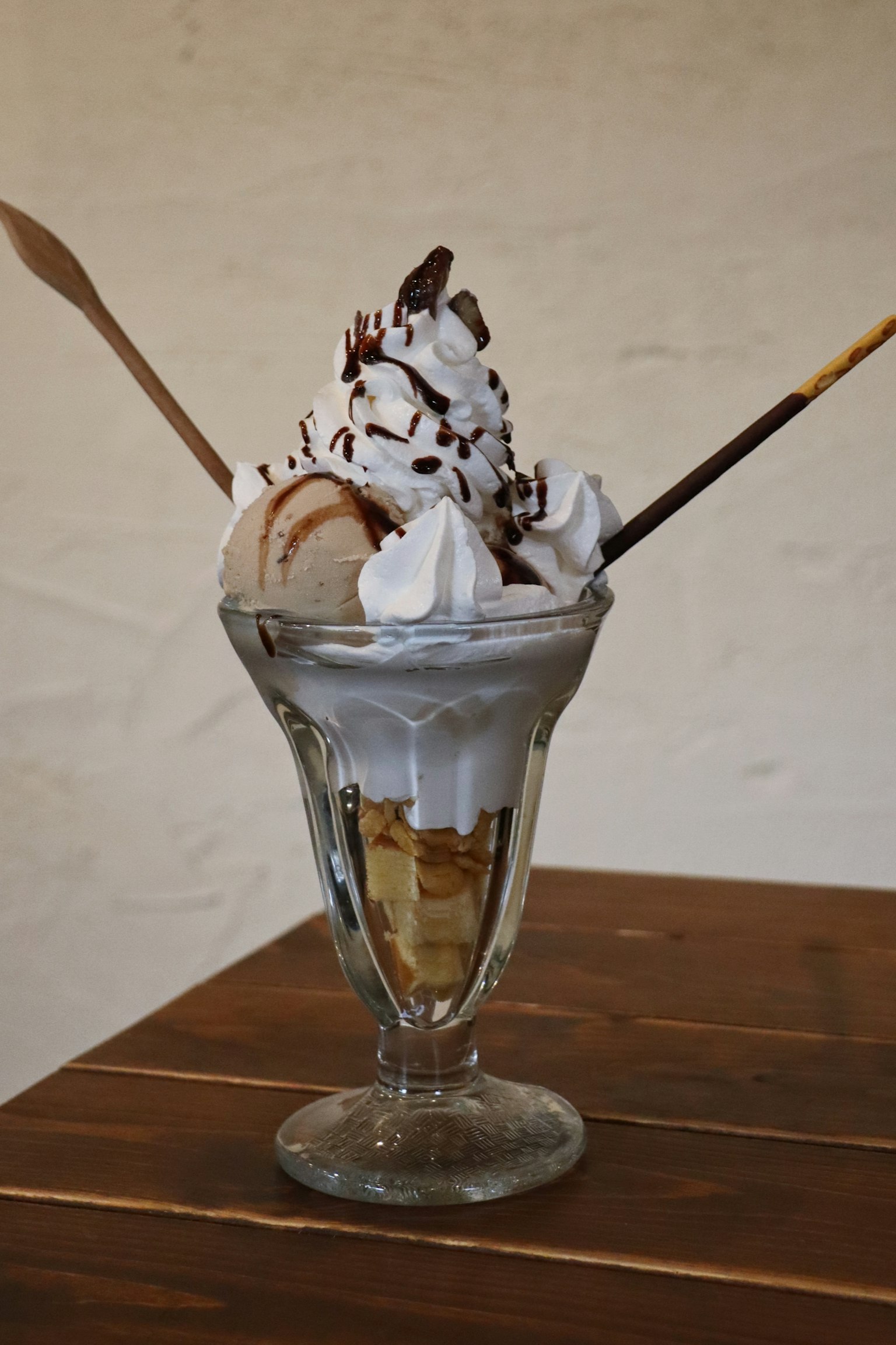 Puding sundae es krim yang dihiasi dengan krim kocok dan saus cokelat
