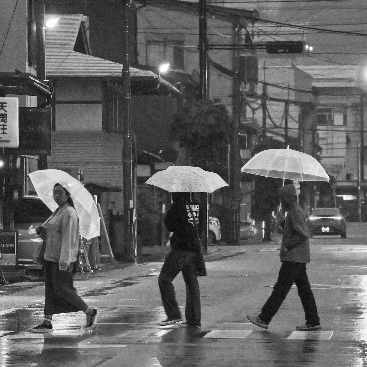 Black and white photo of people walking with umbrellas in the rain