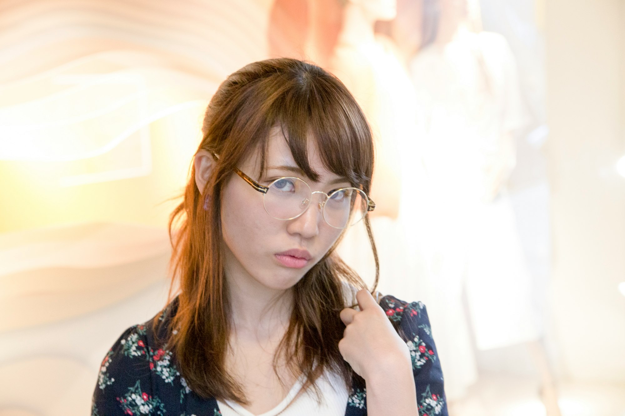 portrait of a woman with round glasses touching her hair
