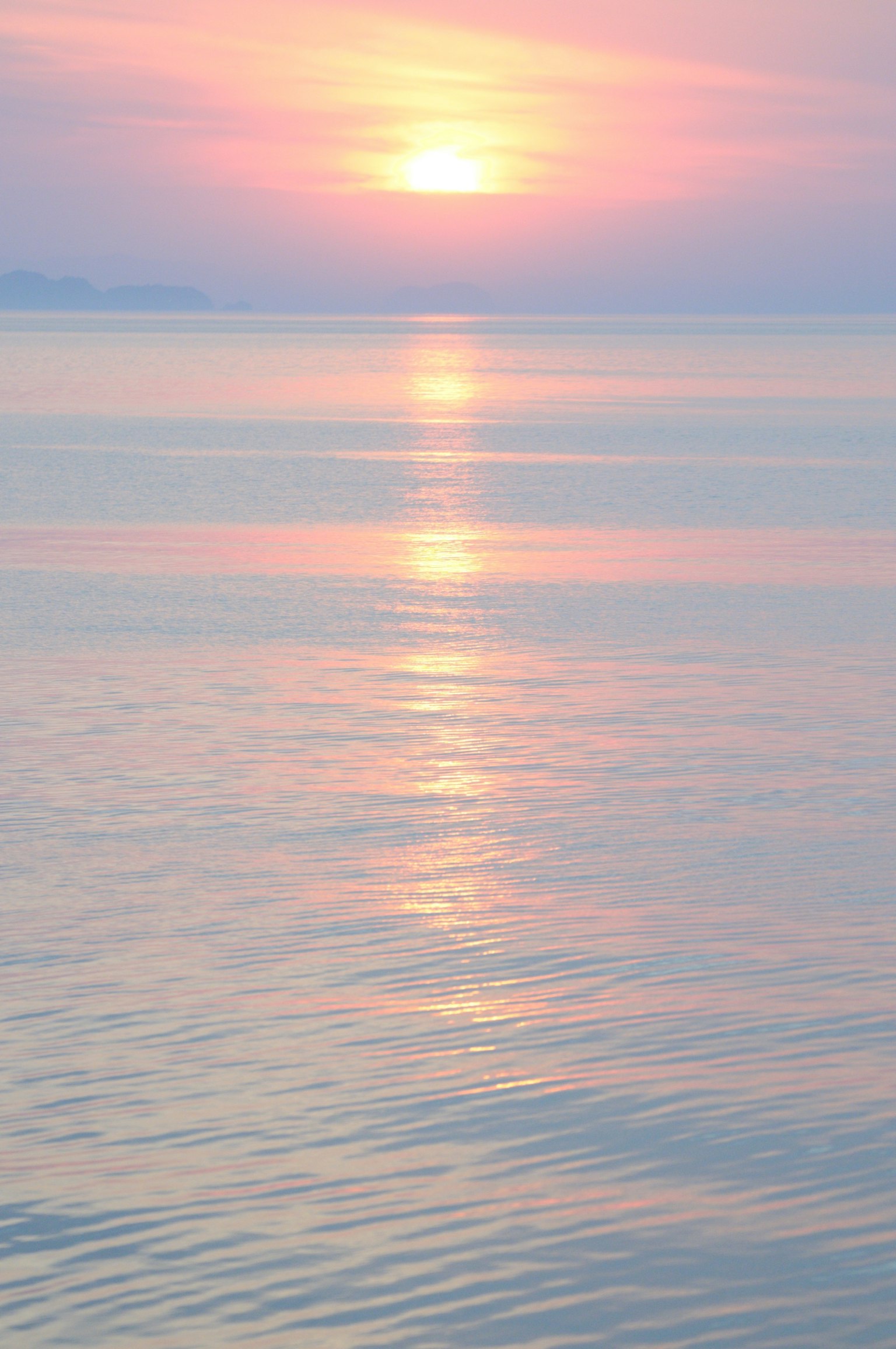 Sanfter Sonnenuntergang, der sich auf ruhigem Wasser mit Pastellfarben spiegelt