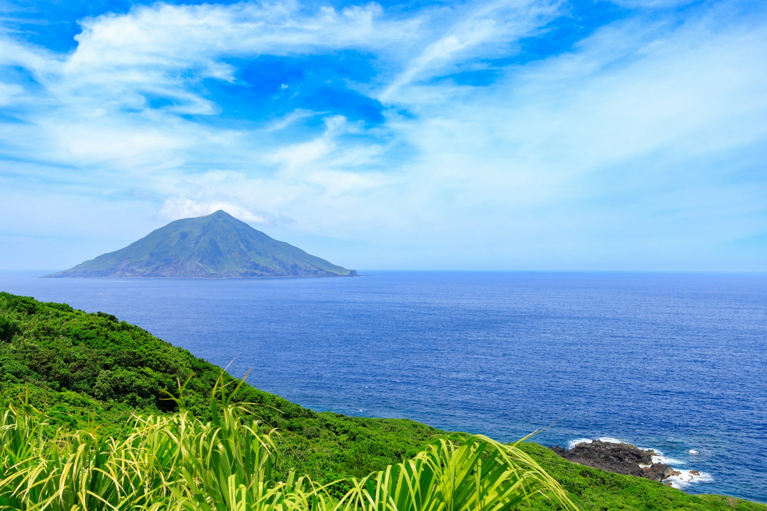 Scenic view of a small island with blue ocean and sky