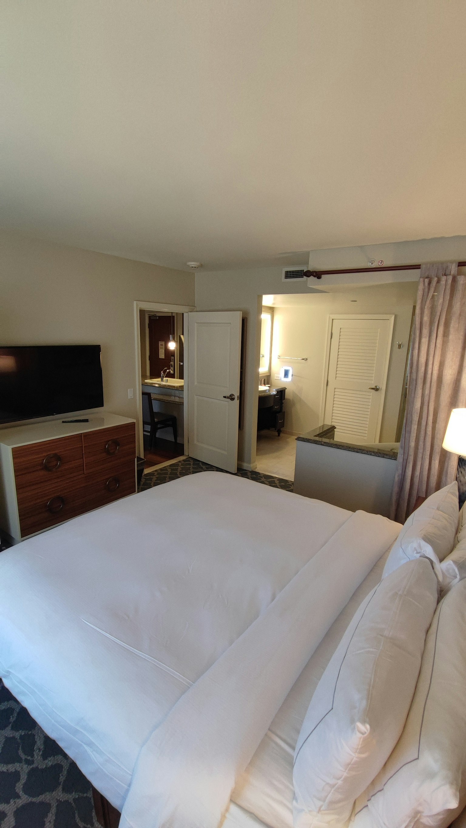 Intérieur de chambre lumineuse avec lit blanc, télévision, meubles et portes
