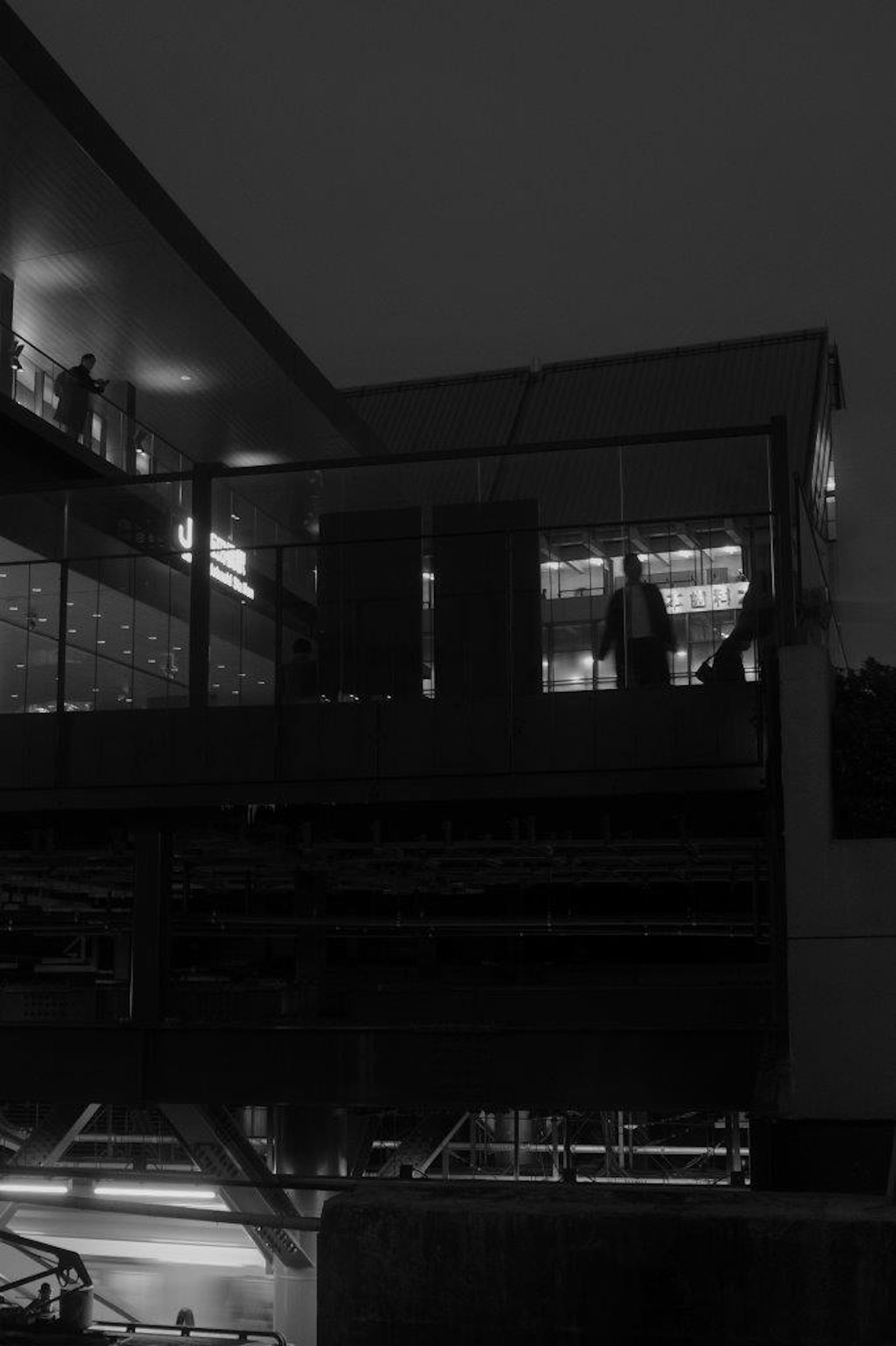 Silhouetten von Menschen in einer dunklen urbanen Landschaft mit Glasstrukturen