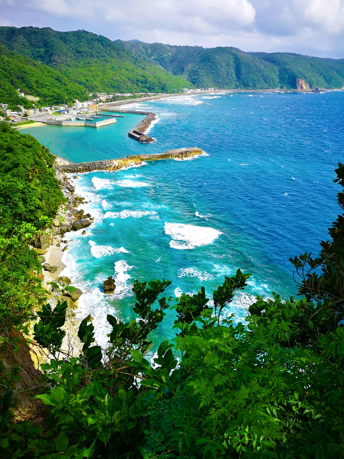 從綠色懸崖俯瞰的海岸線，碧藍海水與白色浪花