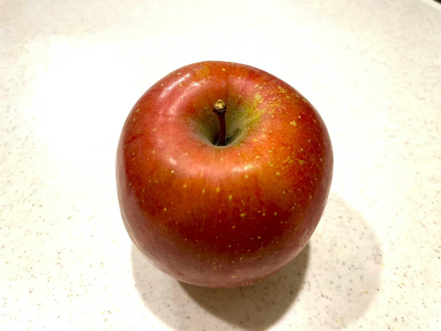 Una manzana roja vibrante sobre un mostrador blanco