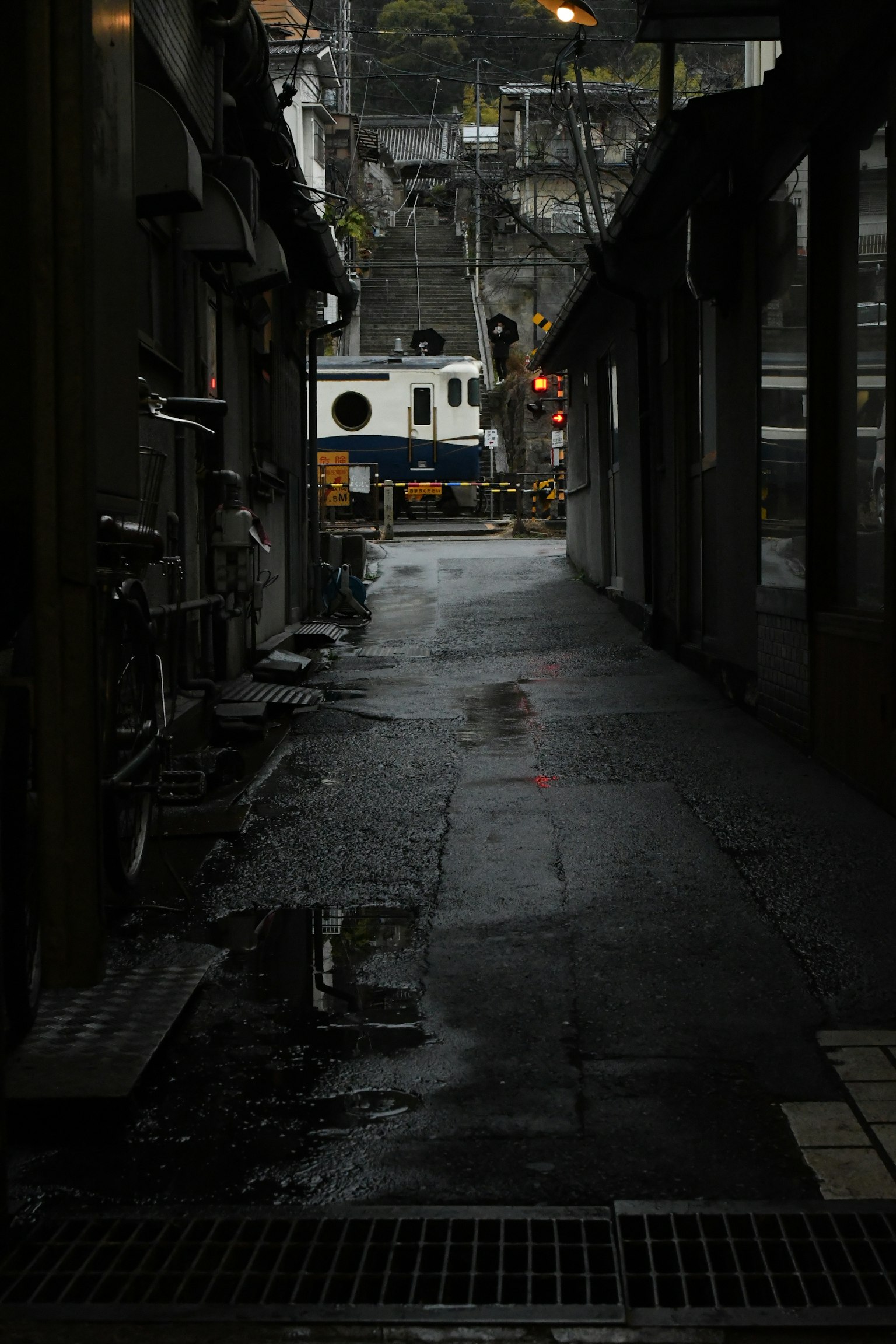 狭い路地に停泊するボートと雨に濡れた舗装