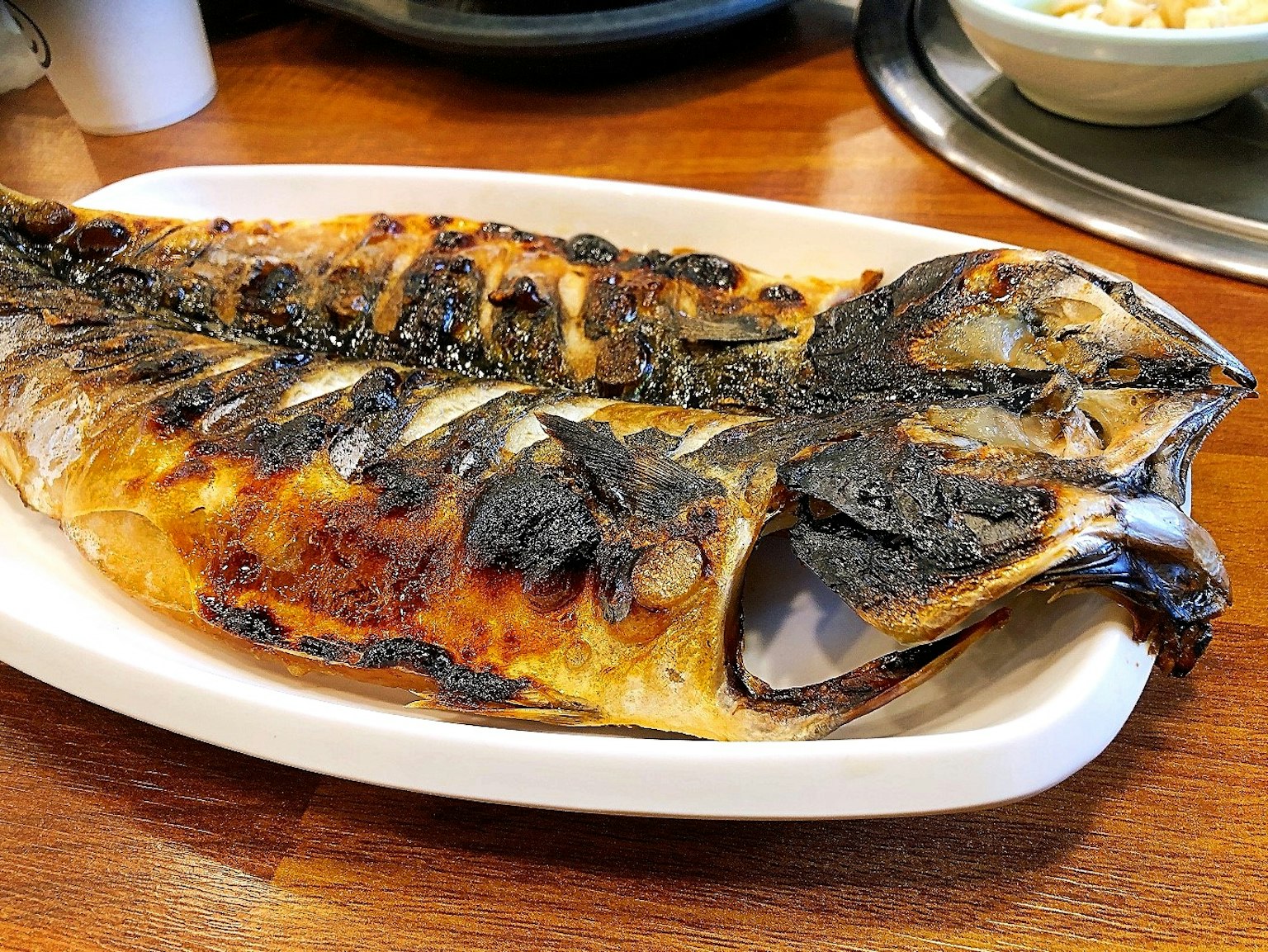Großer gegrillter Fisch auf einem weißen Teller serviert