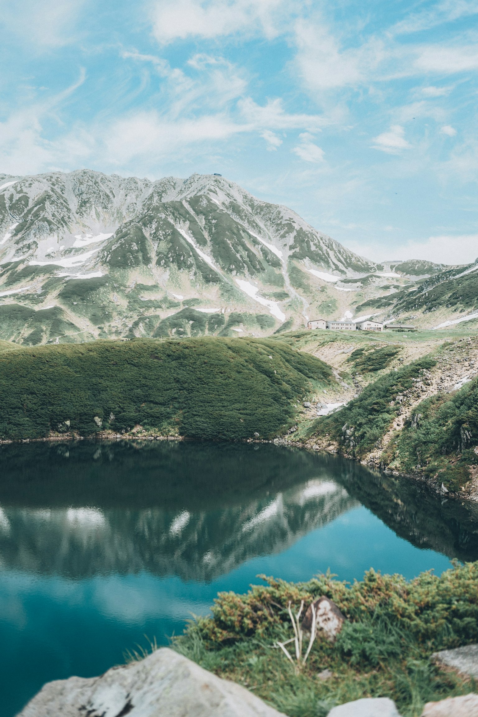 Vista escénica de montañas y lago con reflejos en agua clara