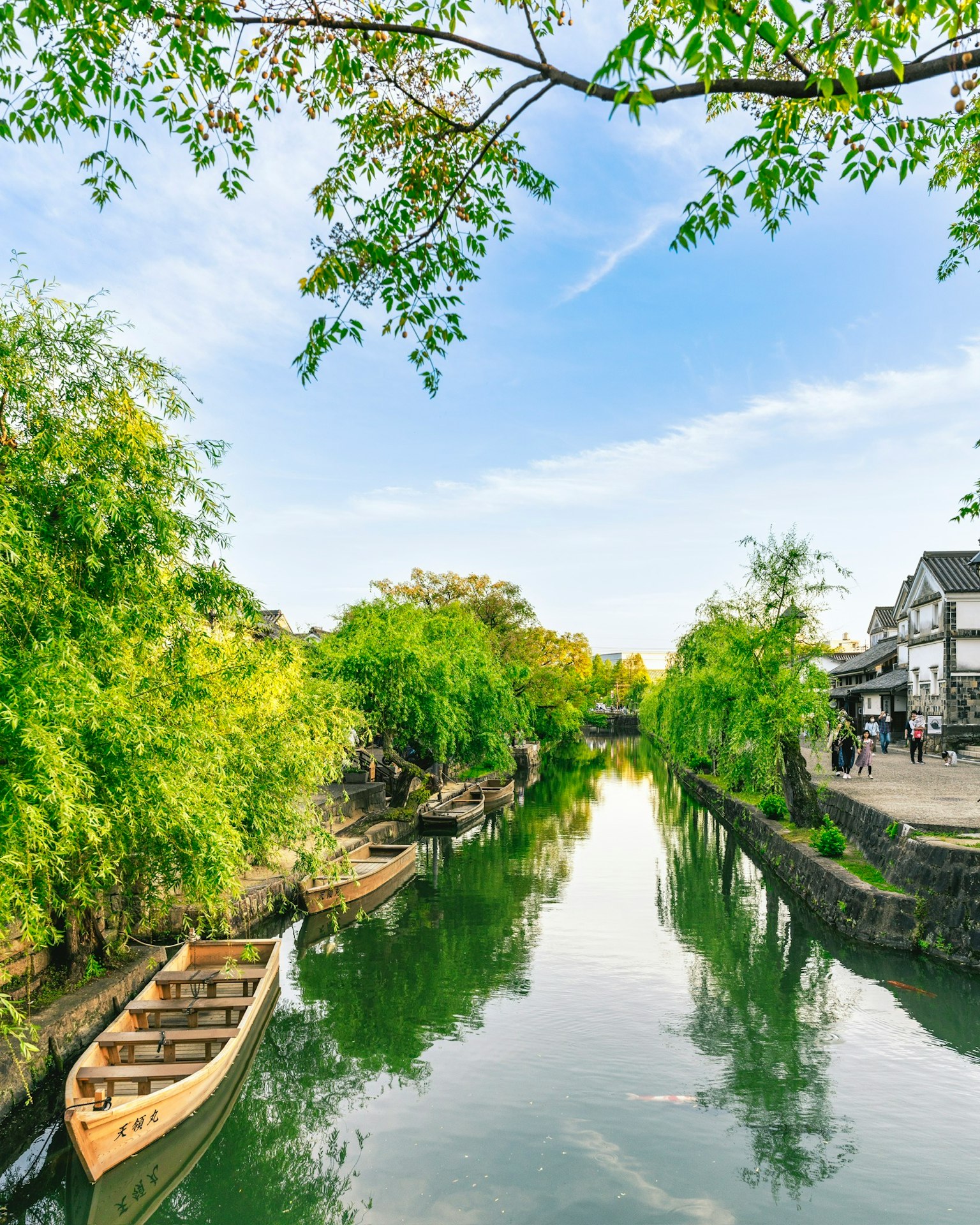 Serene landscape along a canal with lush greenery and small boats