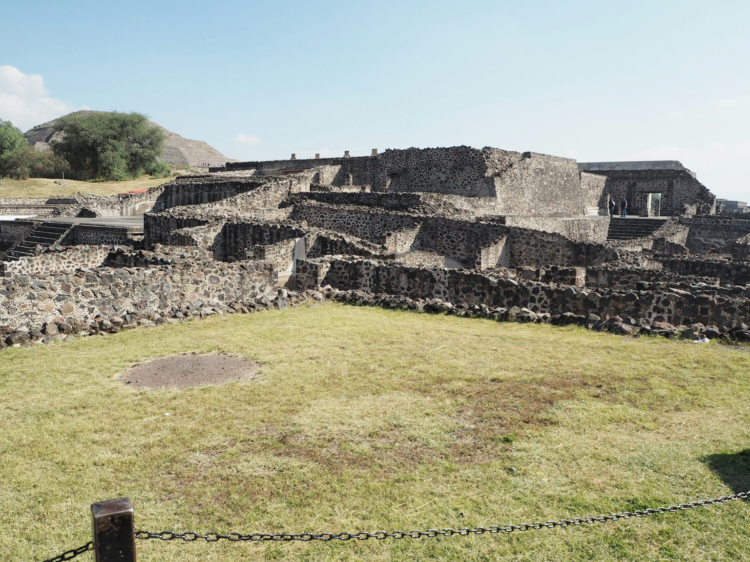 Ancient ruins with stone structures and green grass under a blue sky