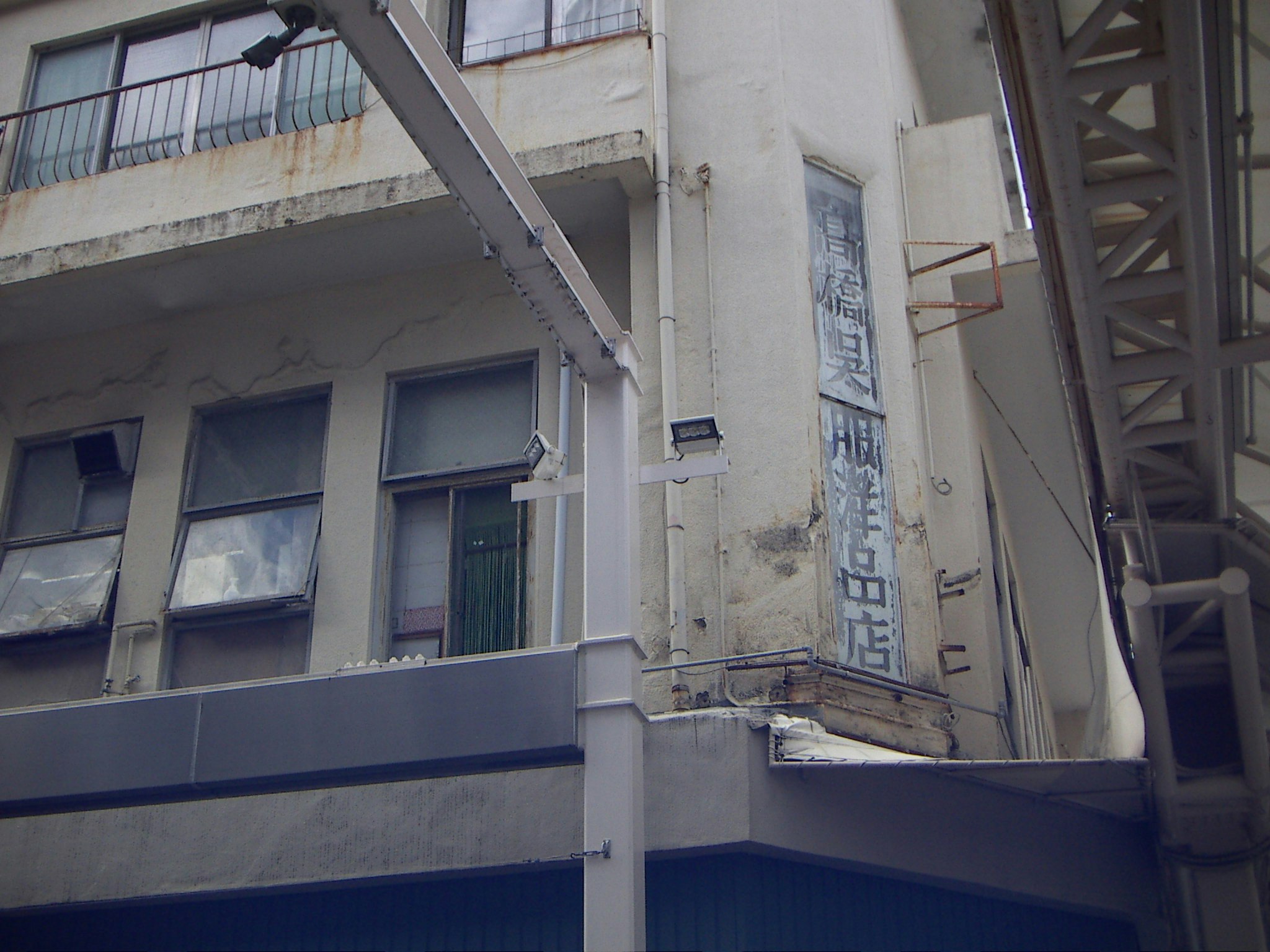 路地のような通路に面した古い建物の外壁と階段