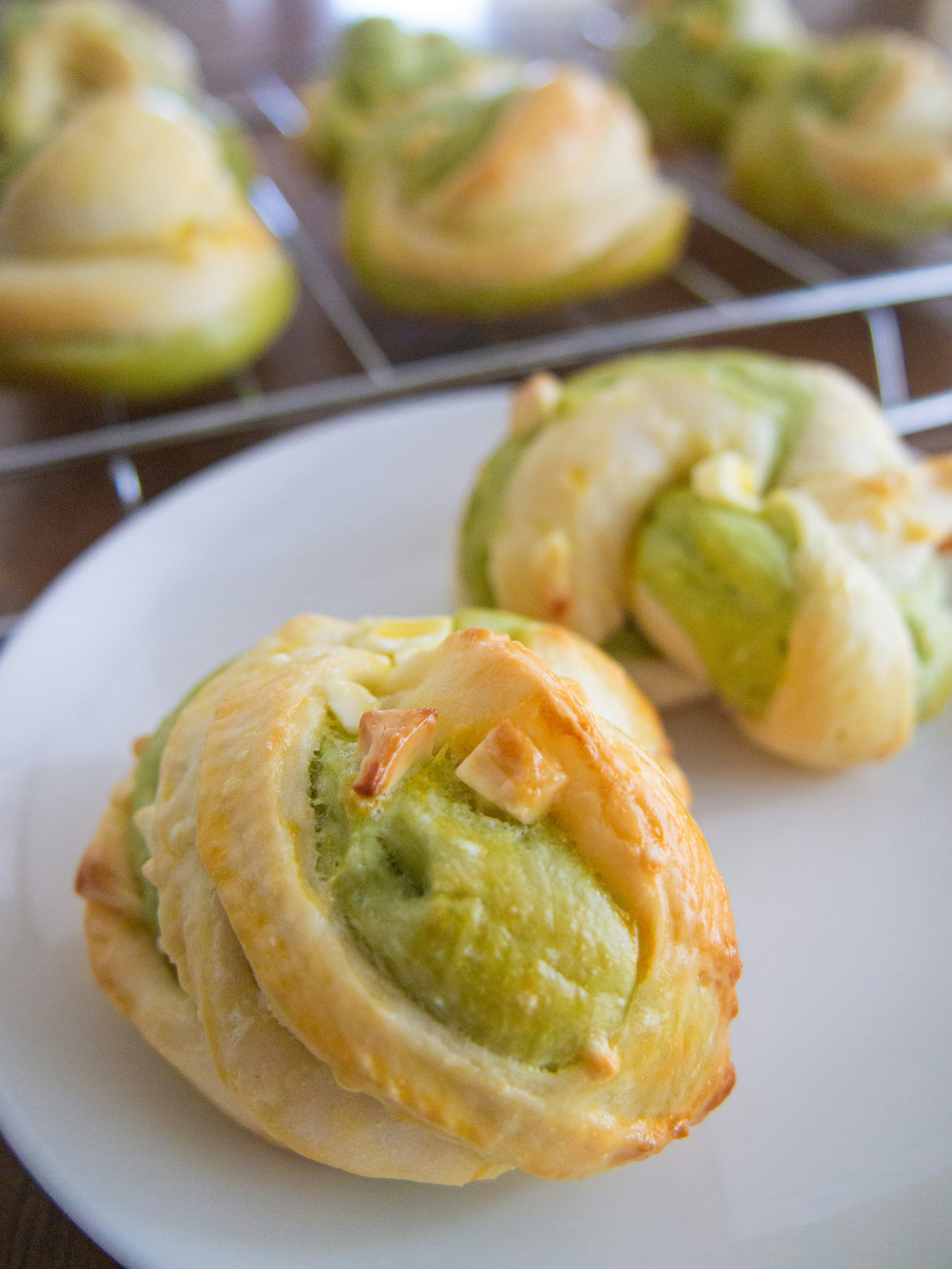 Primo piano di rotolini di pasta sfoglia con ripieno verde su un piatto
