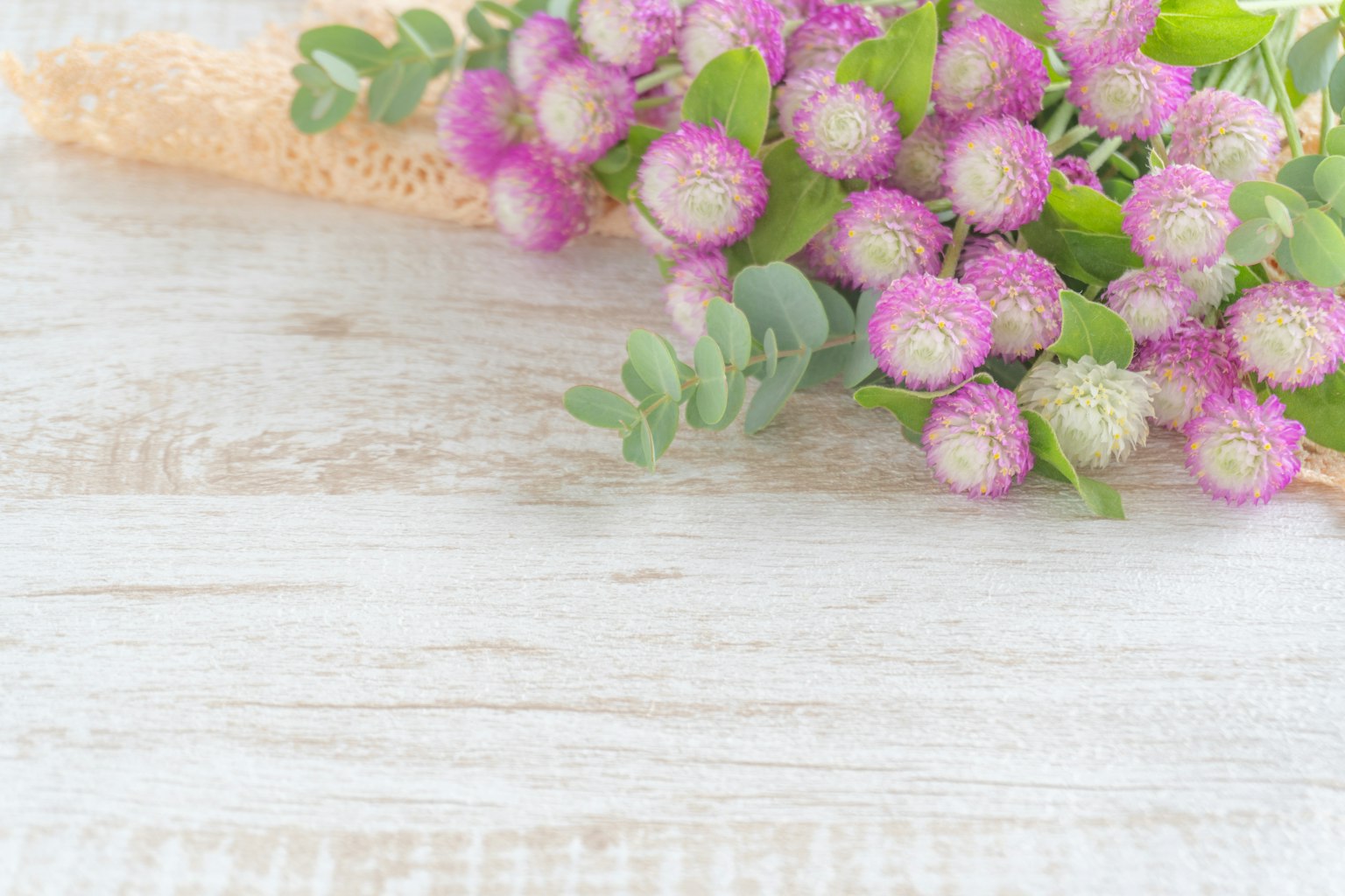 Ein Strauß pinker Blumen mit grünen Blättern auf einem Holzhintergrund