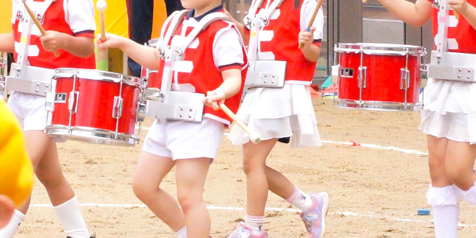 Enfants en uniforme rouge jouant des tambours lors d'un festival sportif