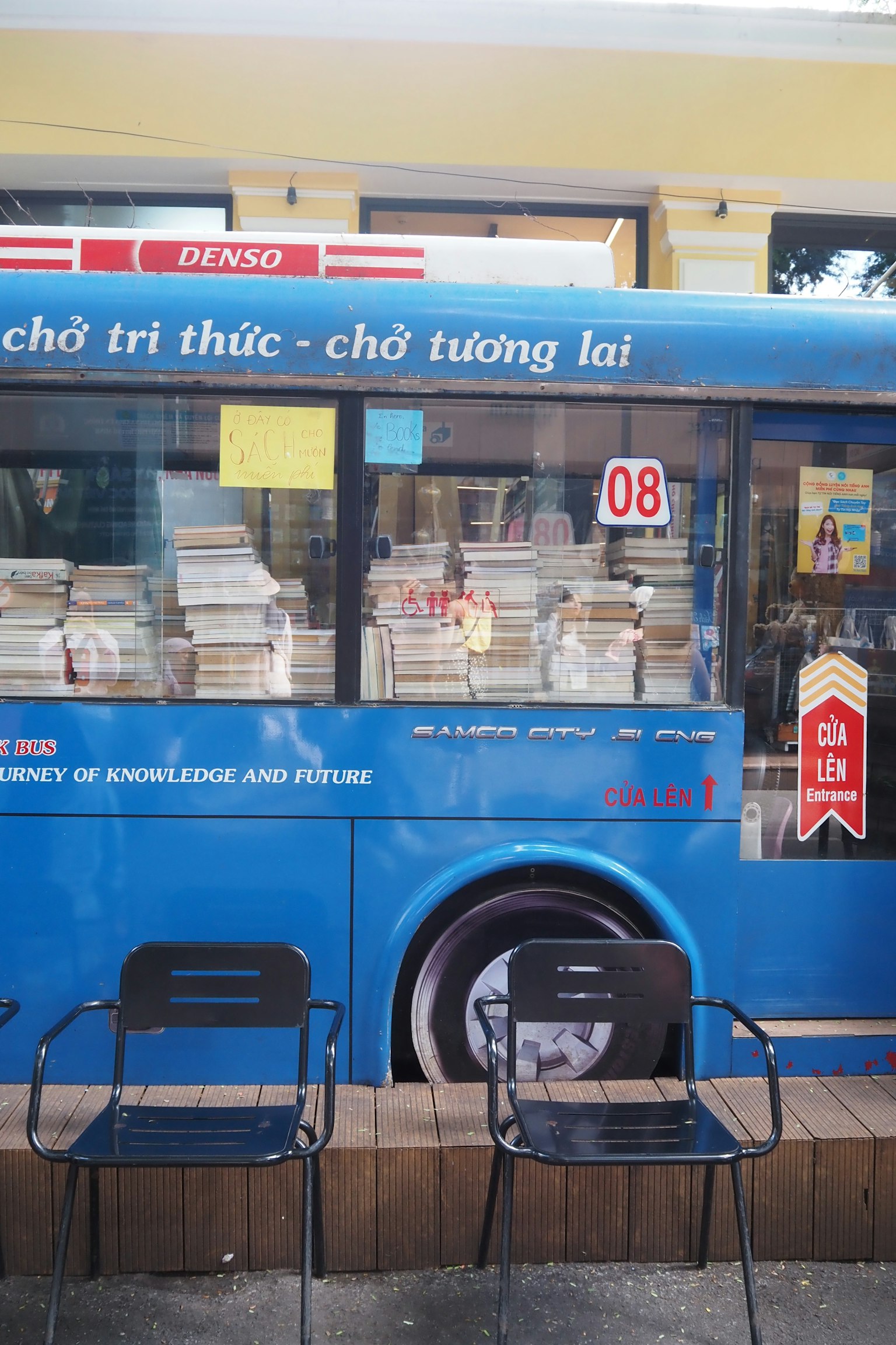 Un autobus blu pieno di libri con due sedie nere davanti