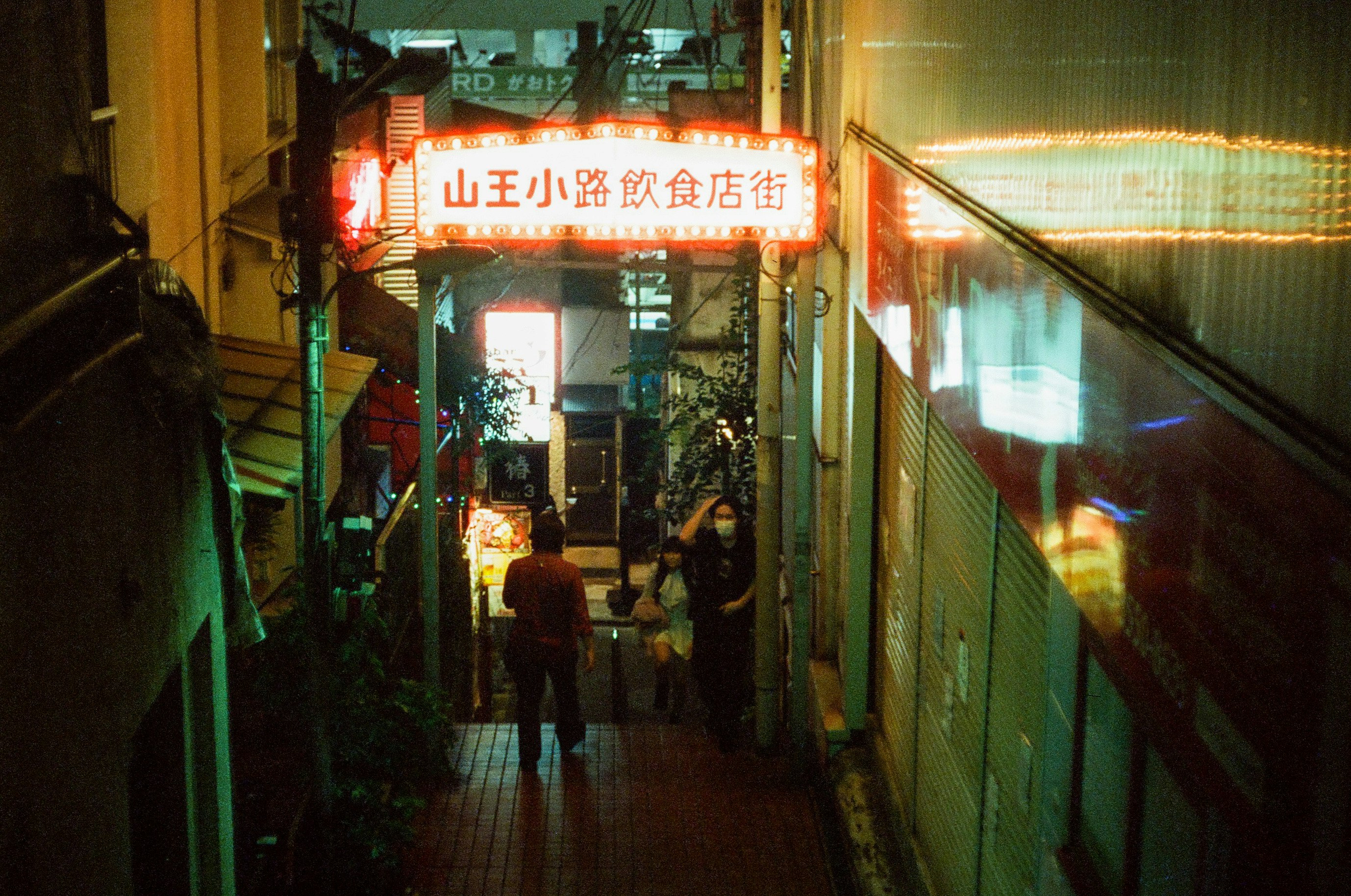 callejón comercial nocturno con letrero luminoso de comida