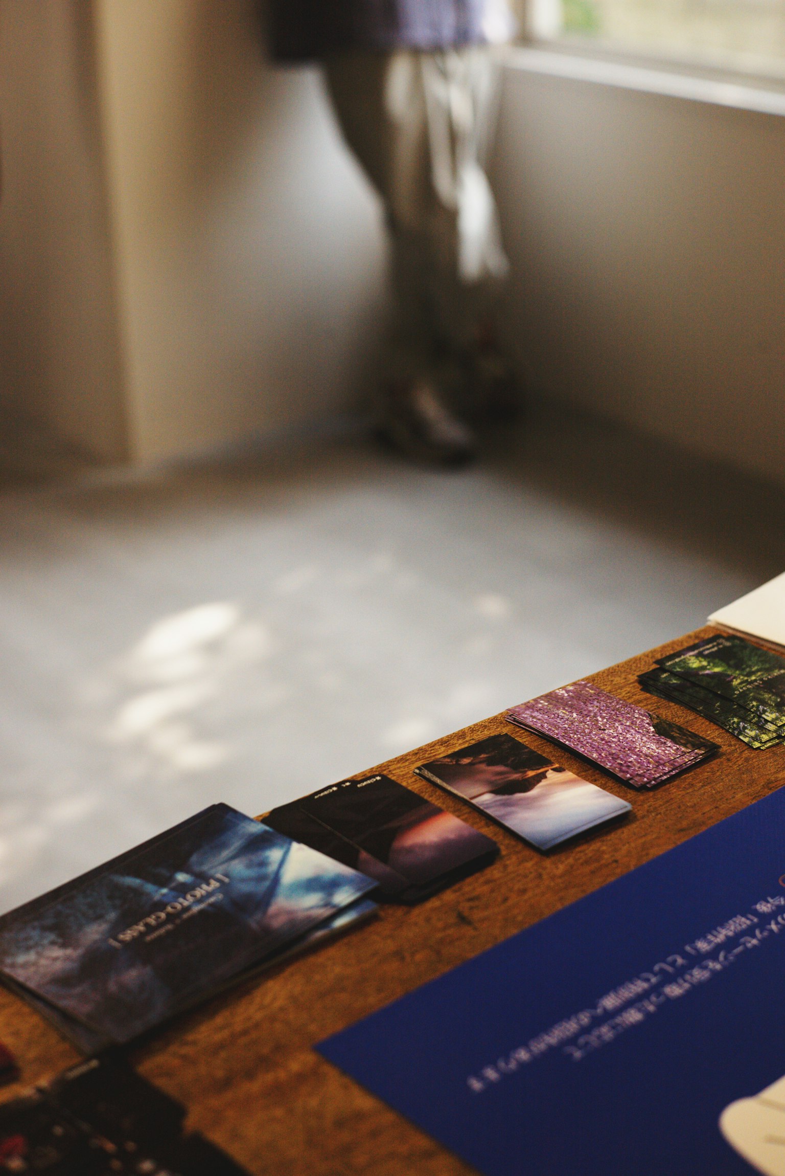 A silhouette of a person standing by the window with cards arranged on a table