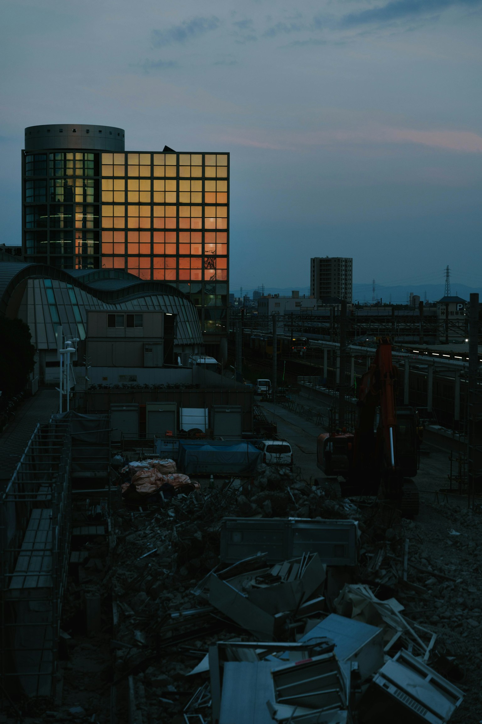 Urban landscape at dusk with orange reflections in windows nearby buildings and debris