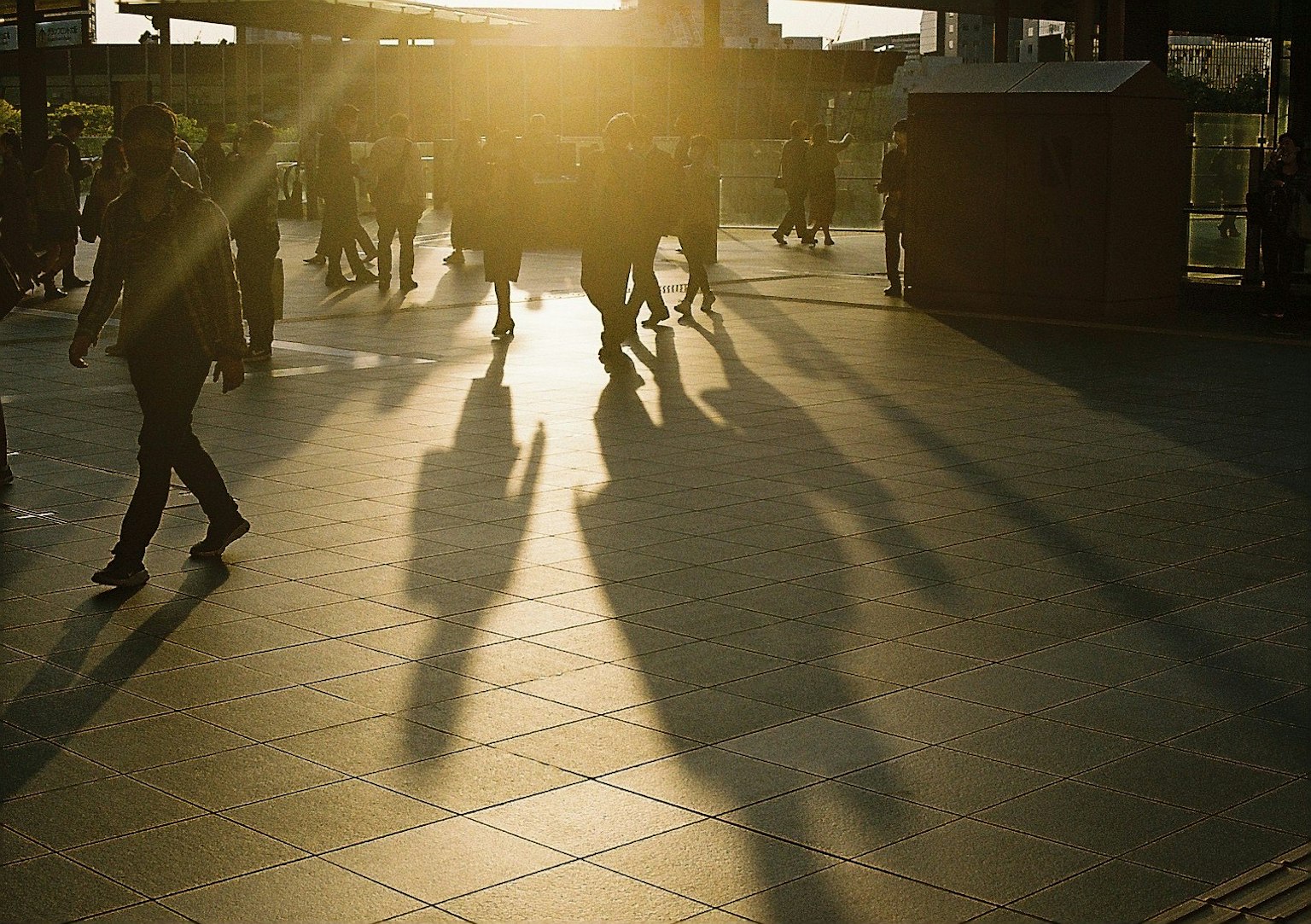 Silhouettes de personnes marchant sur une rue baignée de soleil