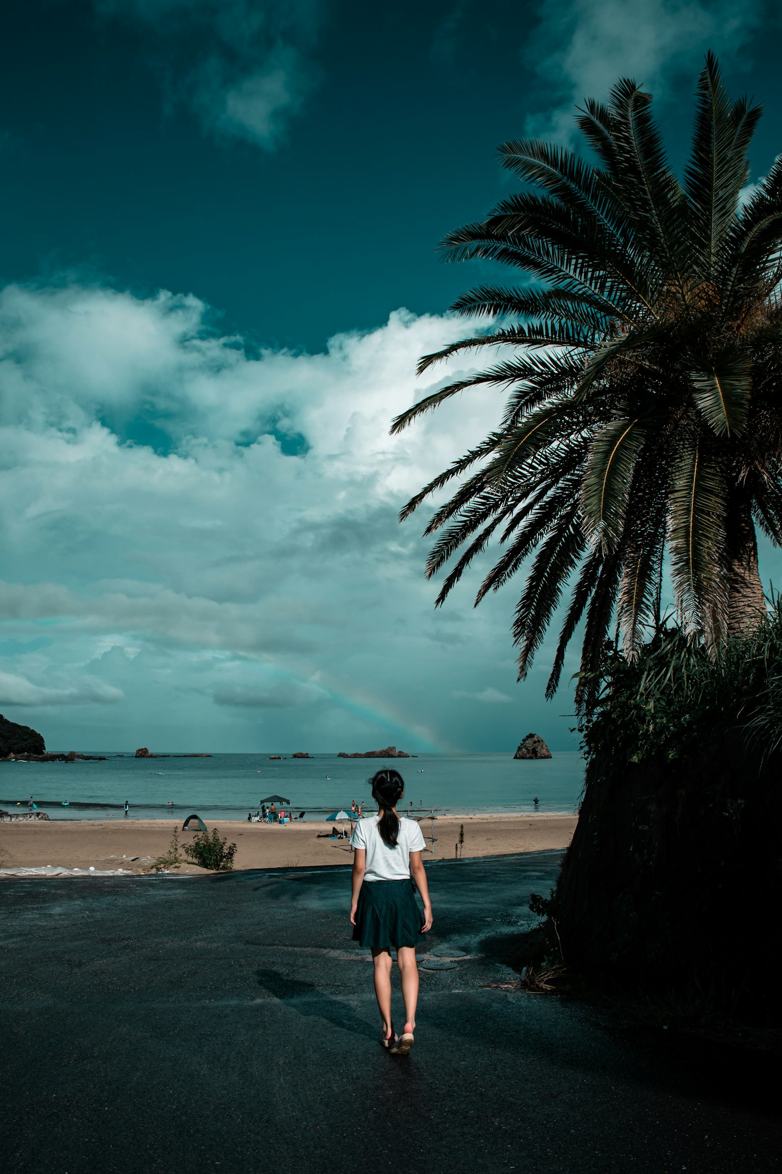A woman walking towards the beach with blue sky and sea in the background