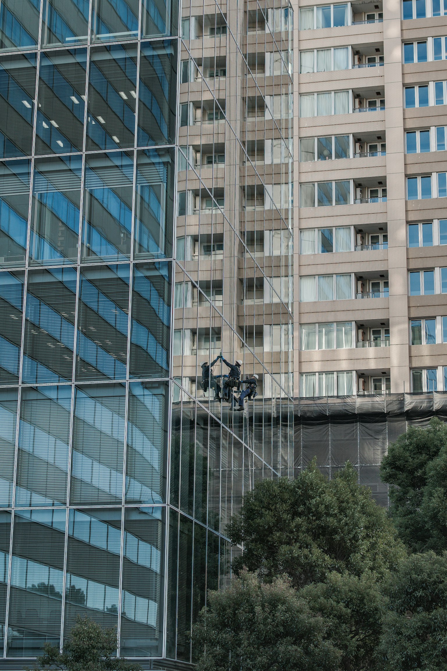 Facciata in vetro di un edificio moderno accanto a una struttura residenziale alta
