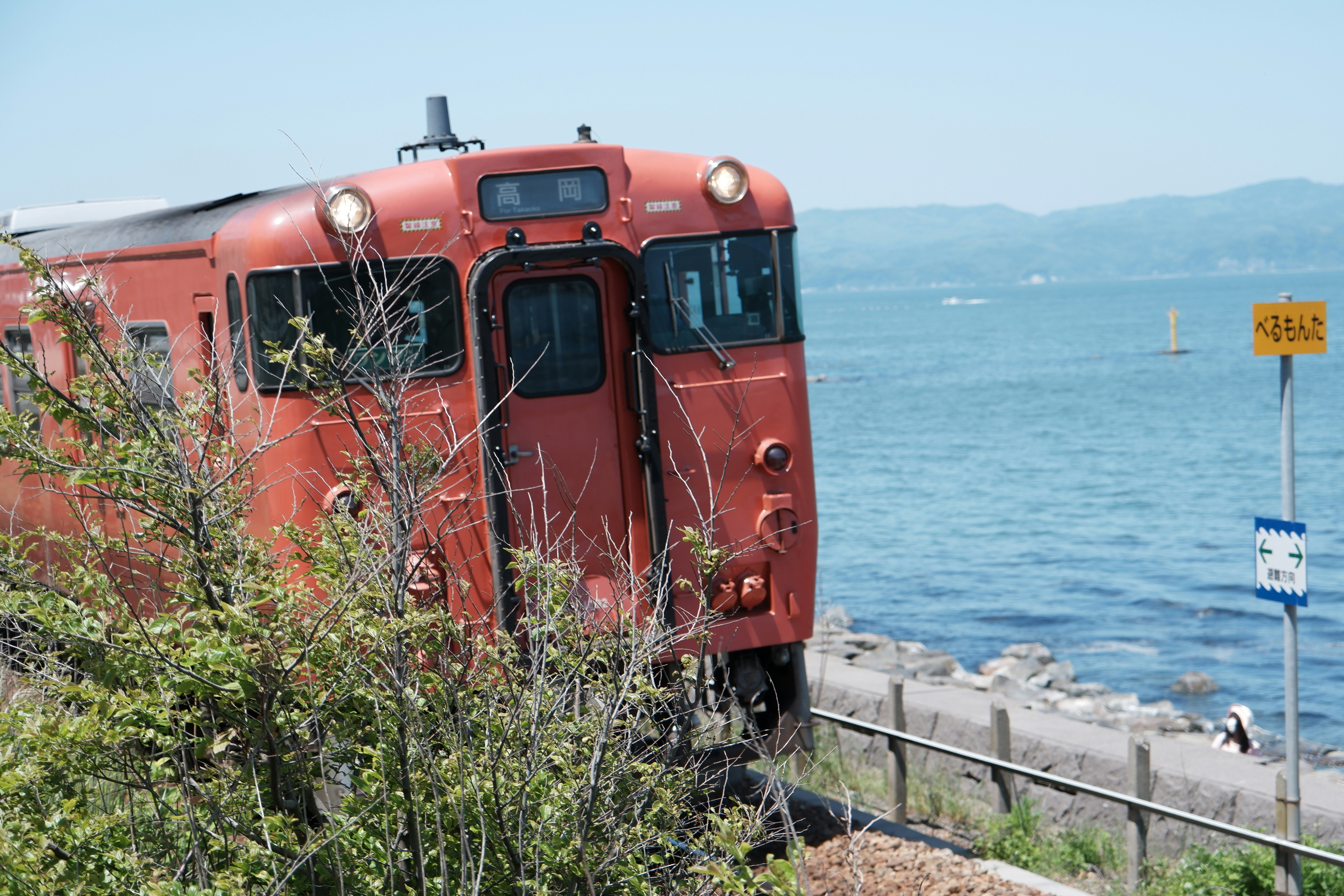 vue de face d’un train rouge roulant le long d’une voie côtière