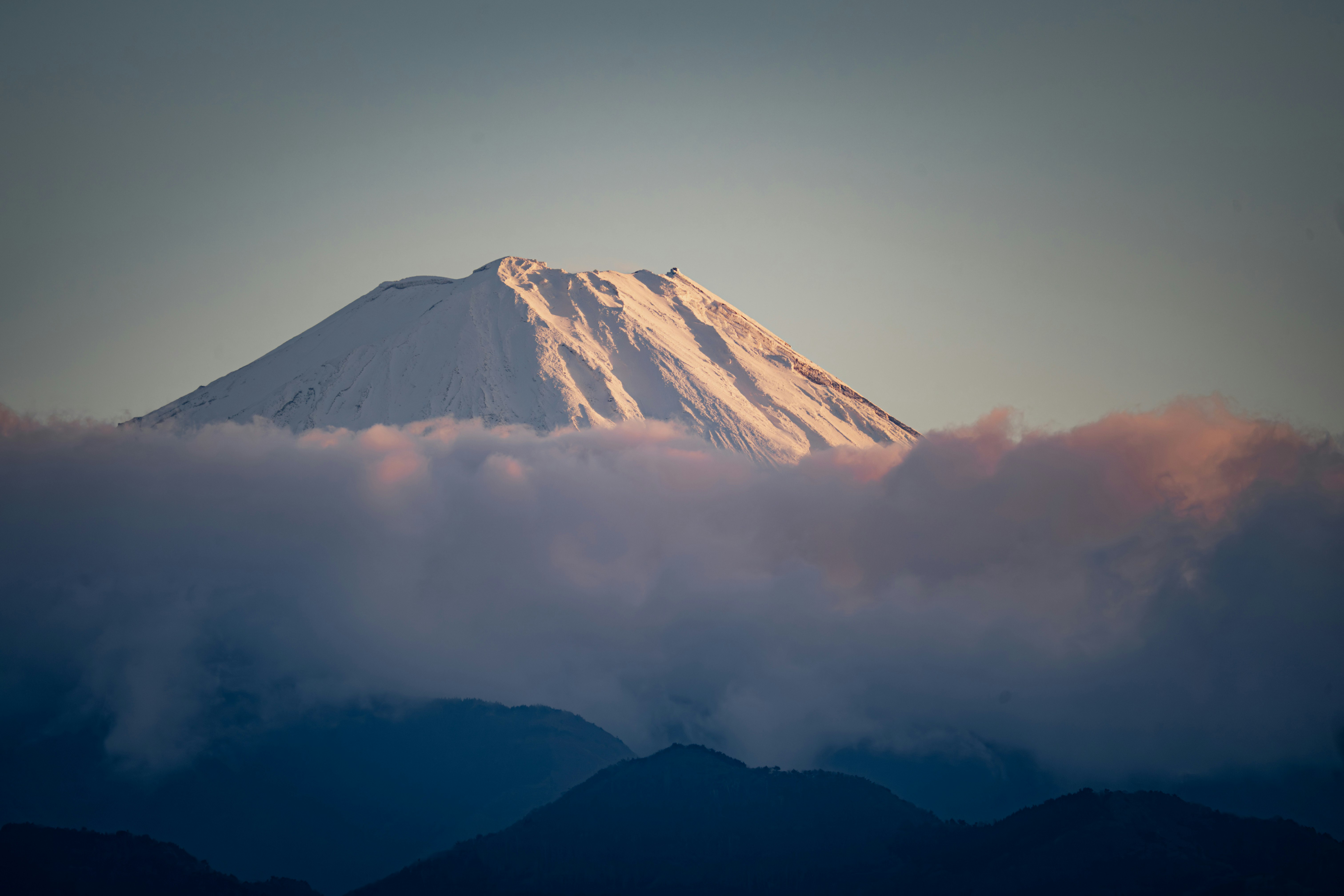雲海の上にそびえる雪を頂いた山の夕景
