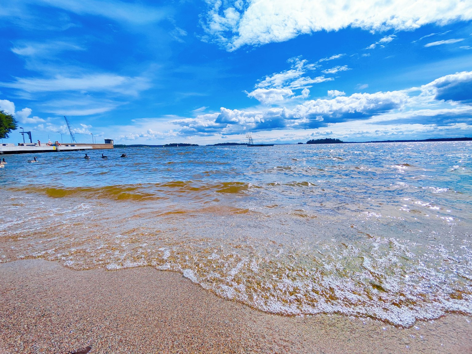 Küstenlandschaft mit blauem Himmel und weißen Wolken über dem Strand