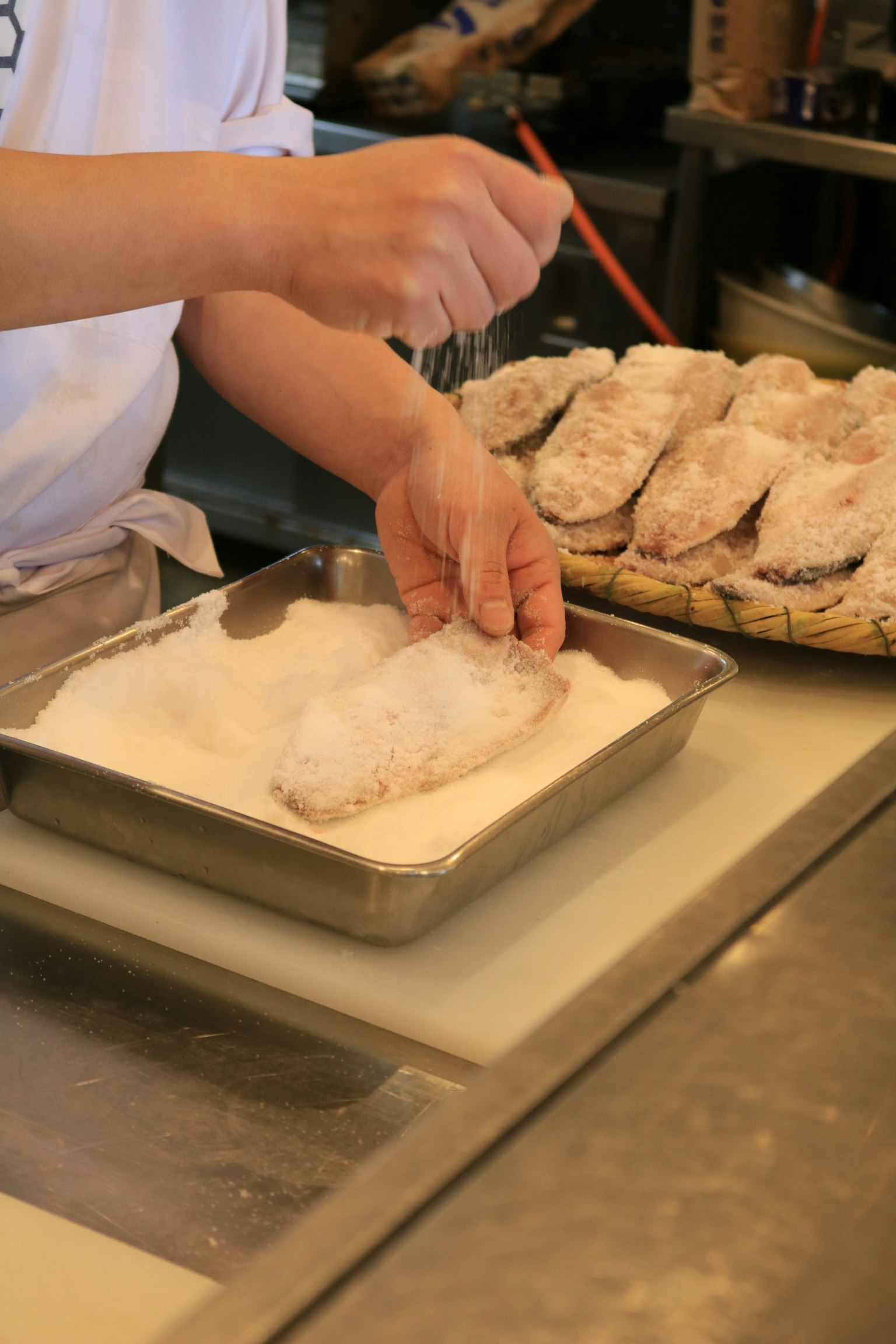 Chef espolvoreando sal sobre un filete de pescado en una cocina