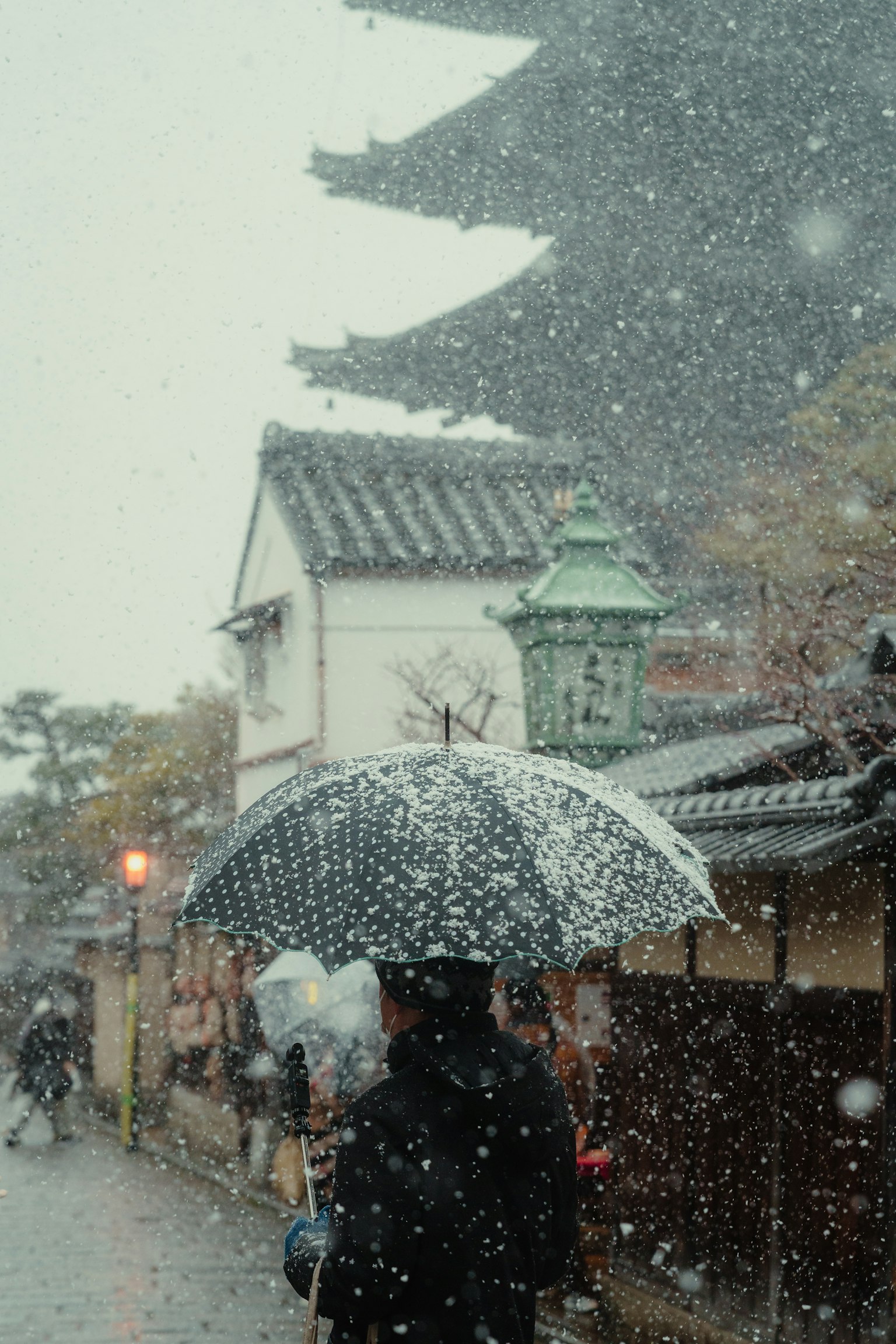 在雪天街景中打着伞的人和传统建筑