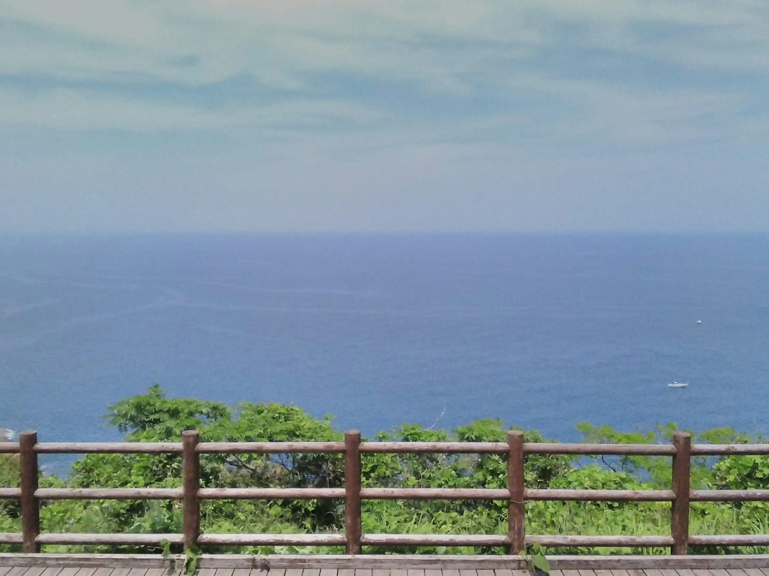 Scenic view of blue ocean with wooden fence