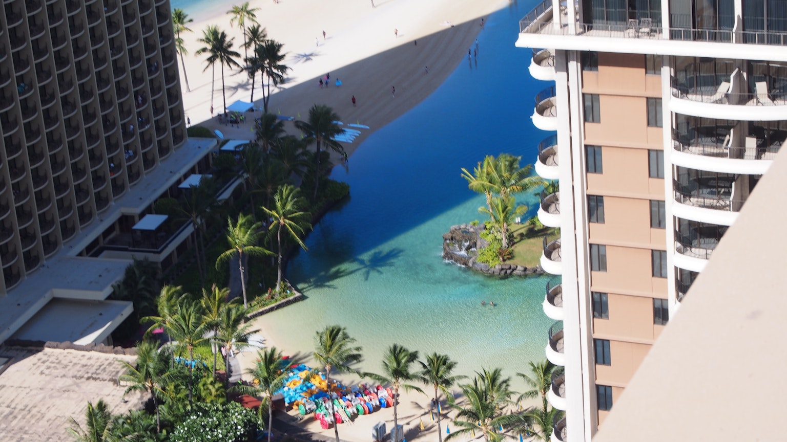 Vista di una spiaggia e di una piscina da un grattacielo con palme e acqua blu