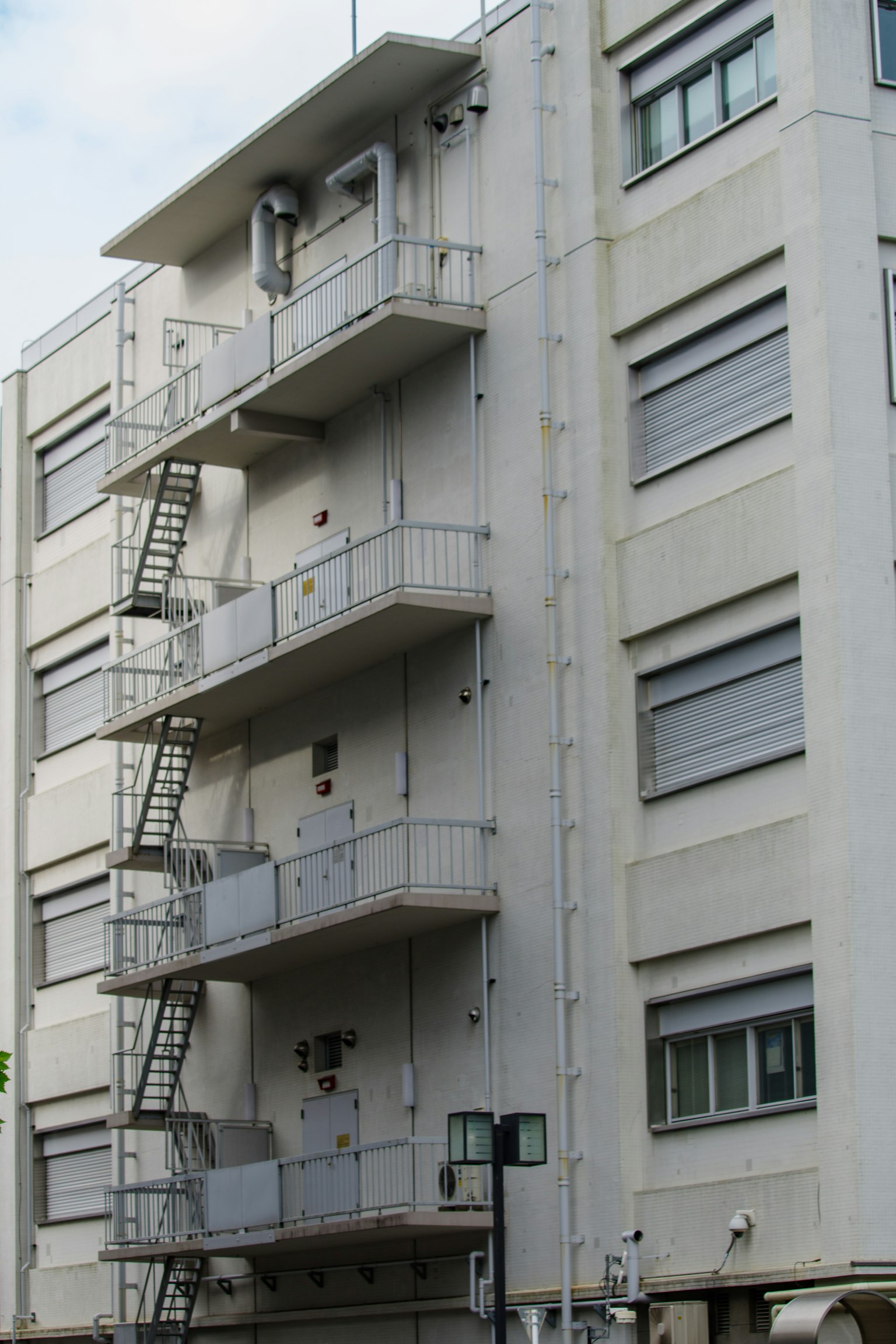 Un bâtiment avec une façade blanche et des escaliers de secours en métal