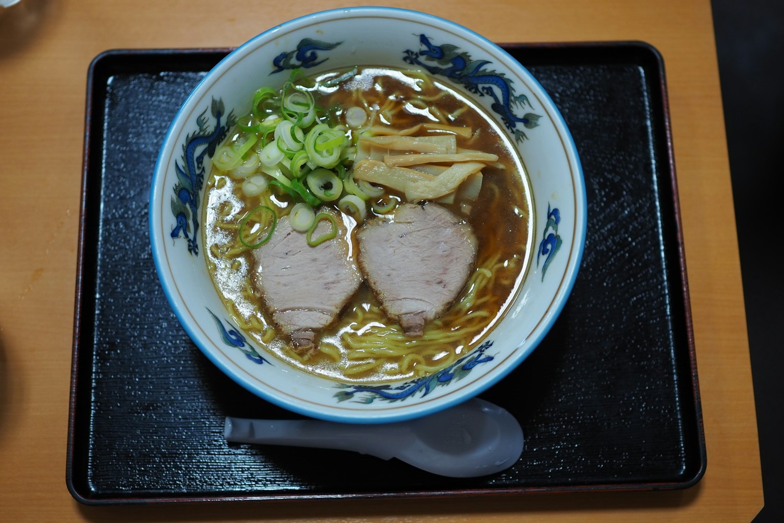Bowl of ramen topped with slices of pork and green onions