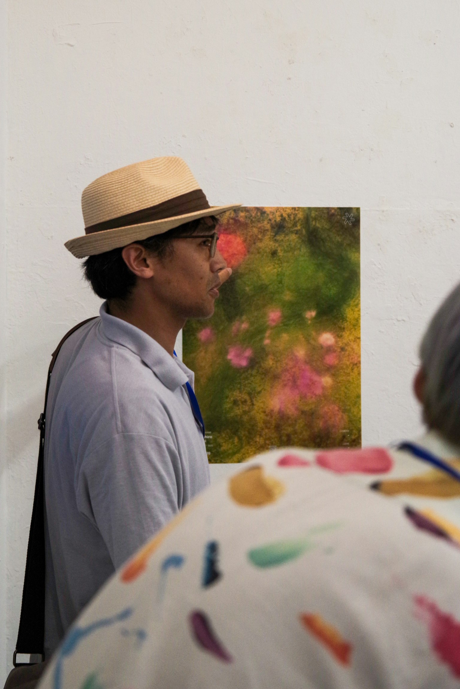 Ein Mann mit Hut steht vor einem Kunstwerk