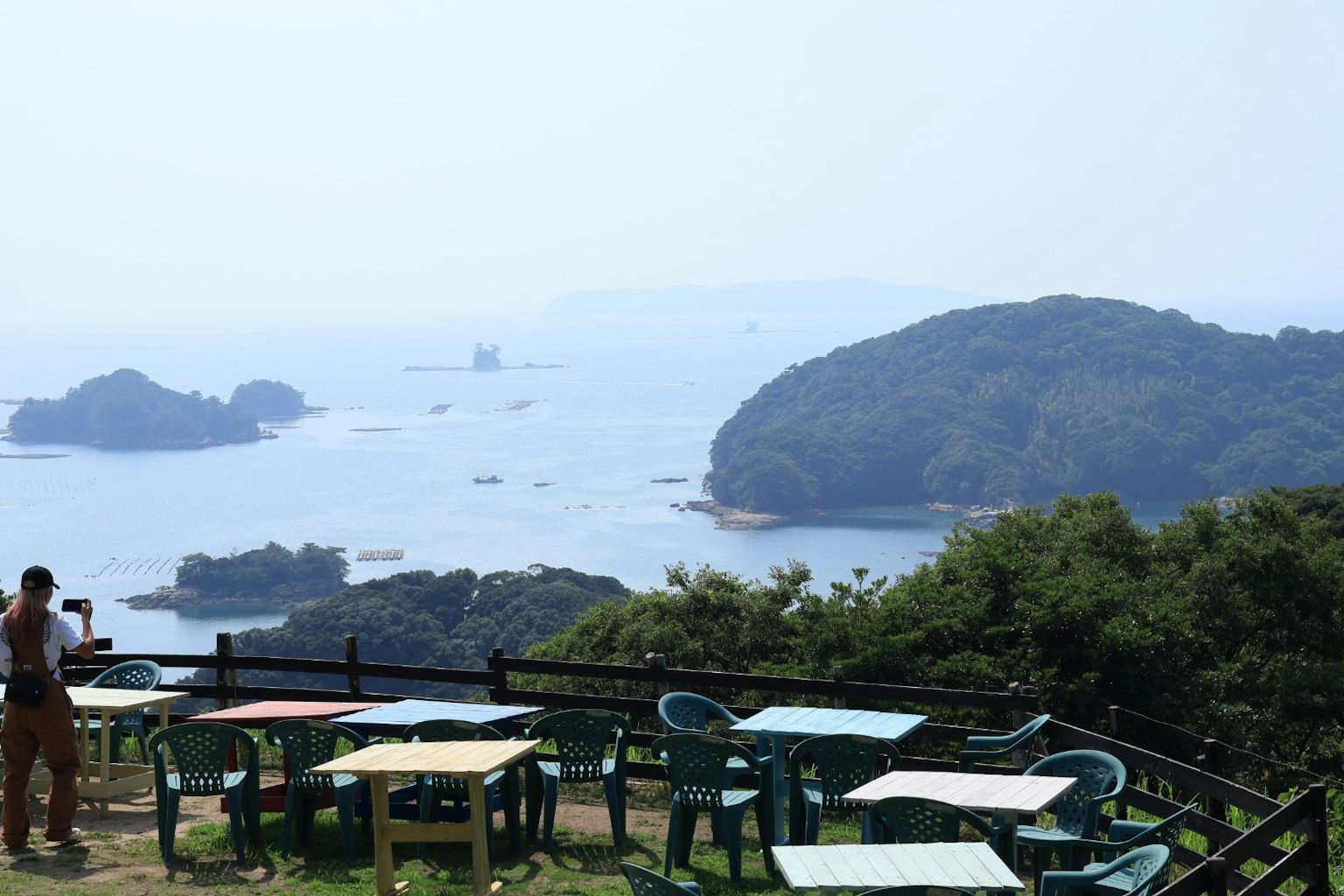 Terrasse de café surplombant la mer arbres verts et chaises bleues