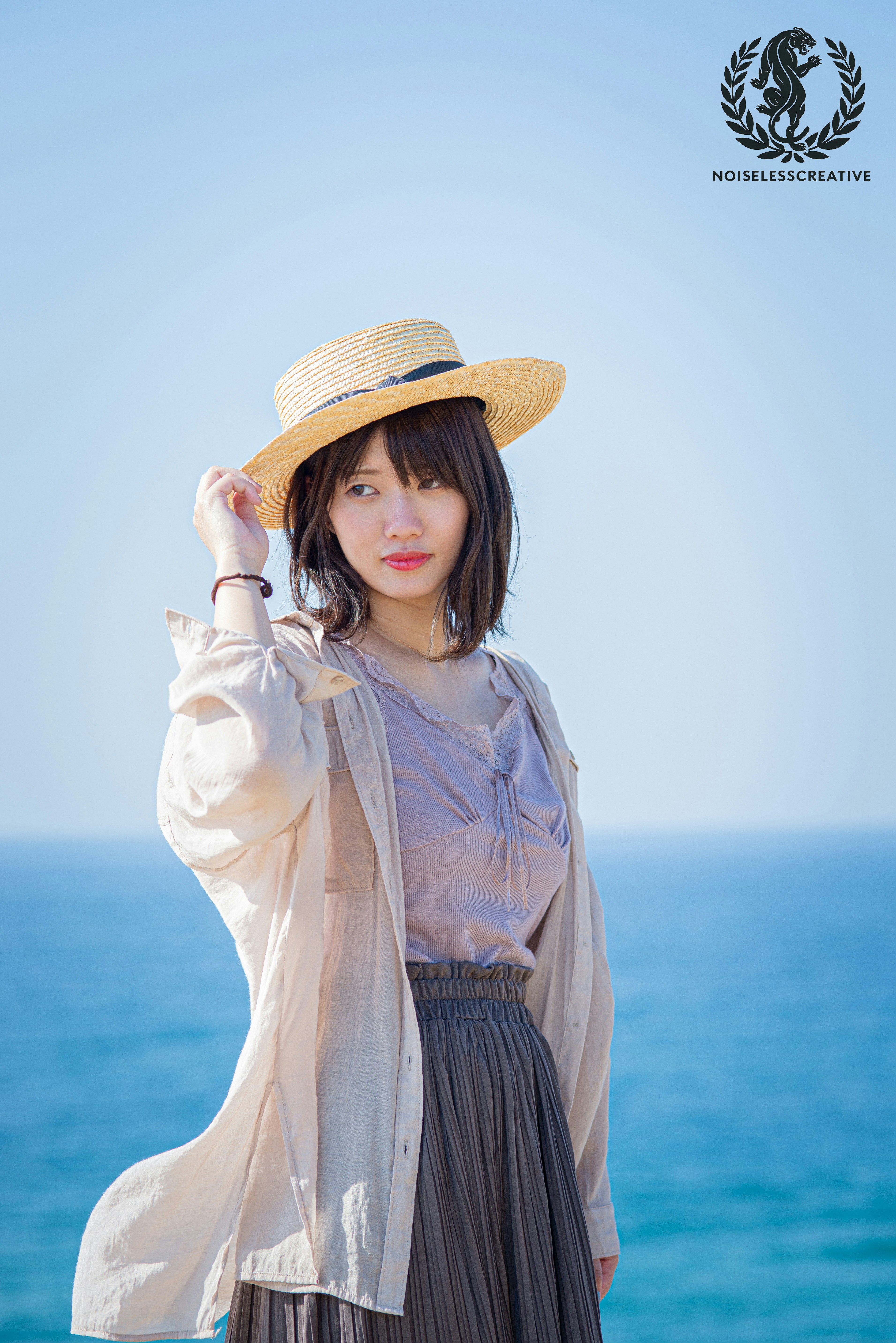 海辺で帽子を手にする女性