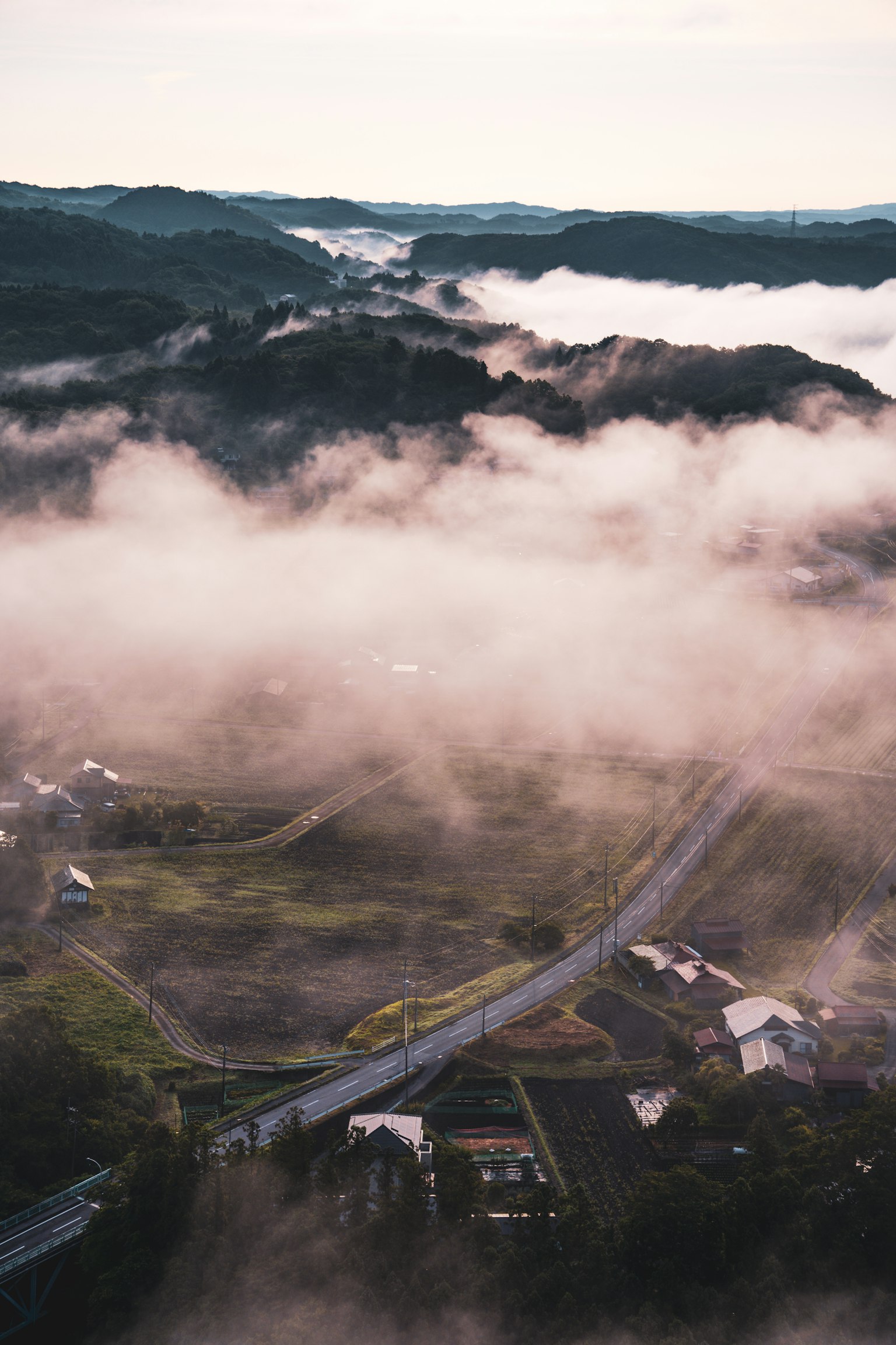 Un paisaje con colinas y una carretera envuelta en niebla